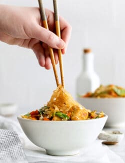 A hand holding chopsticks with glass noodles