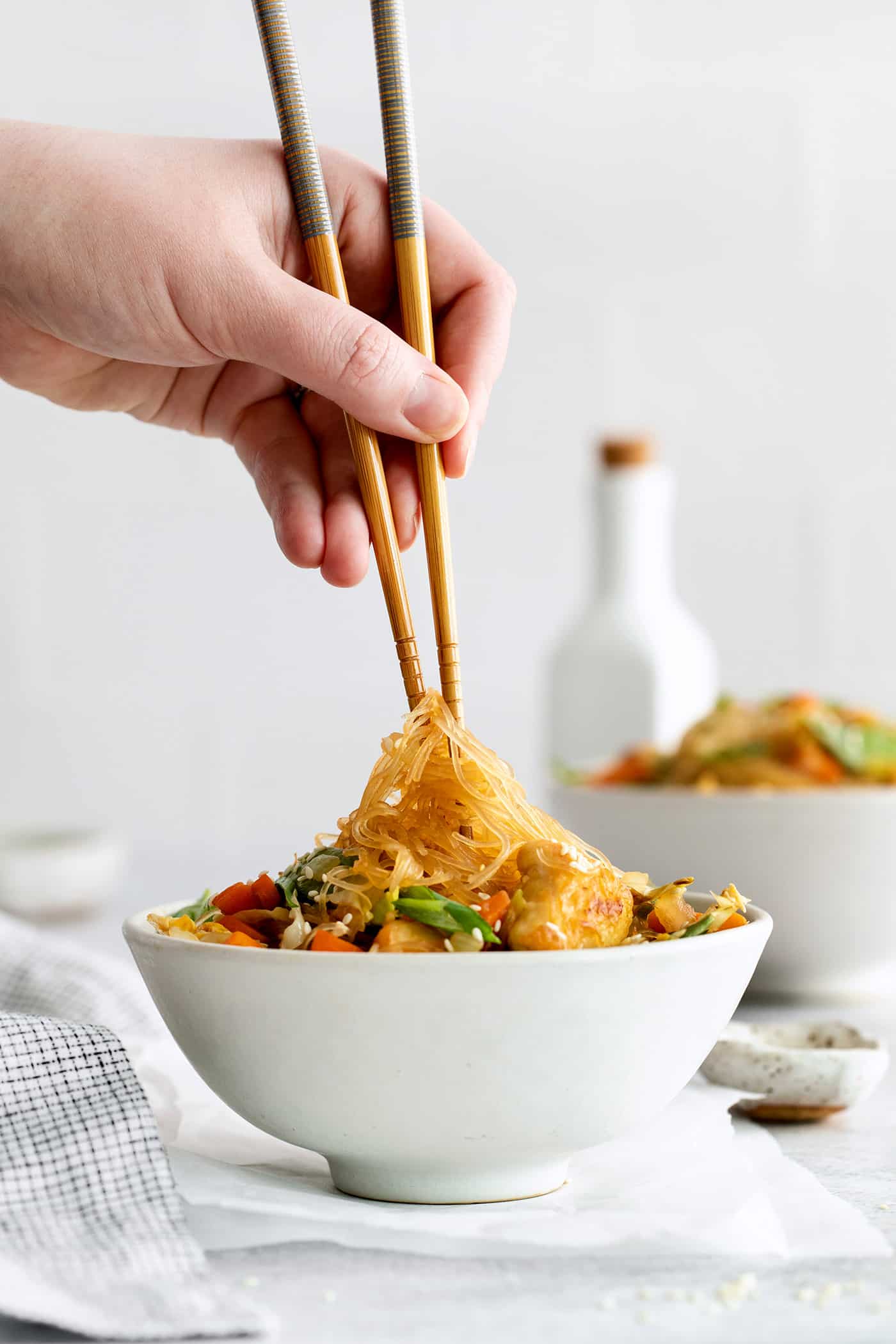 A hand holding chopsticks with glass noodles