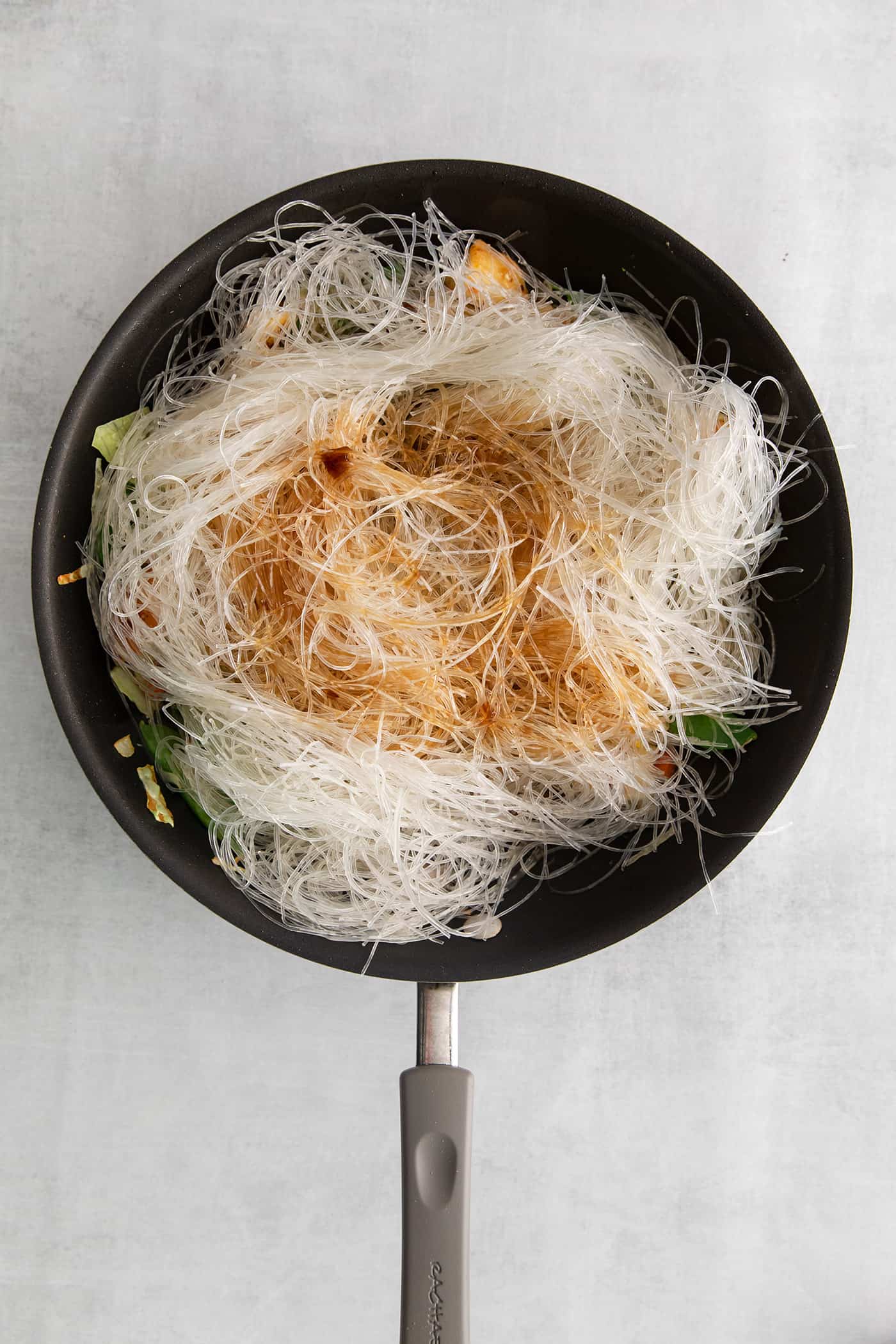 Glass noodles topped with sauce in a skillet