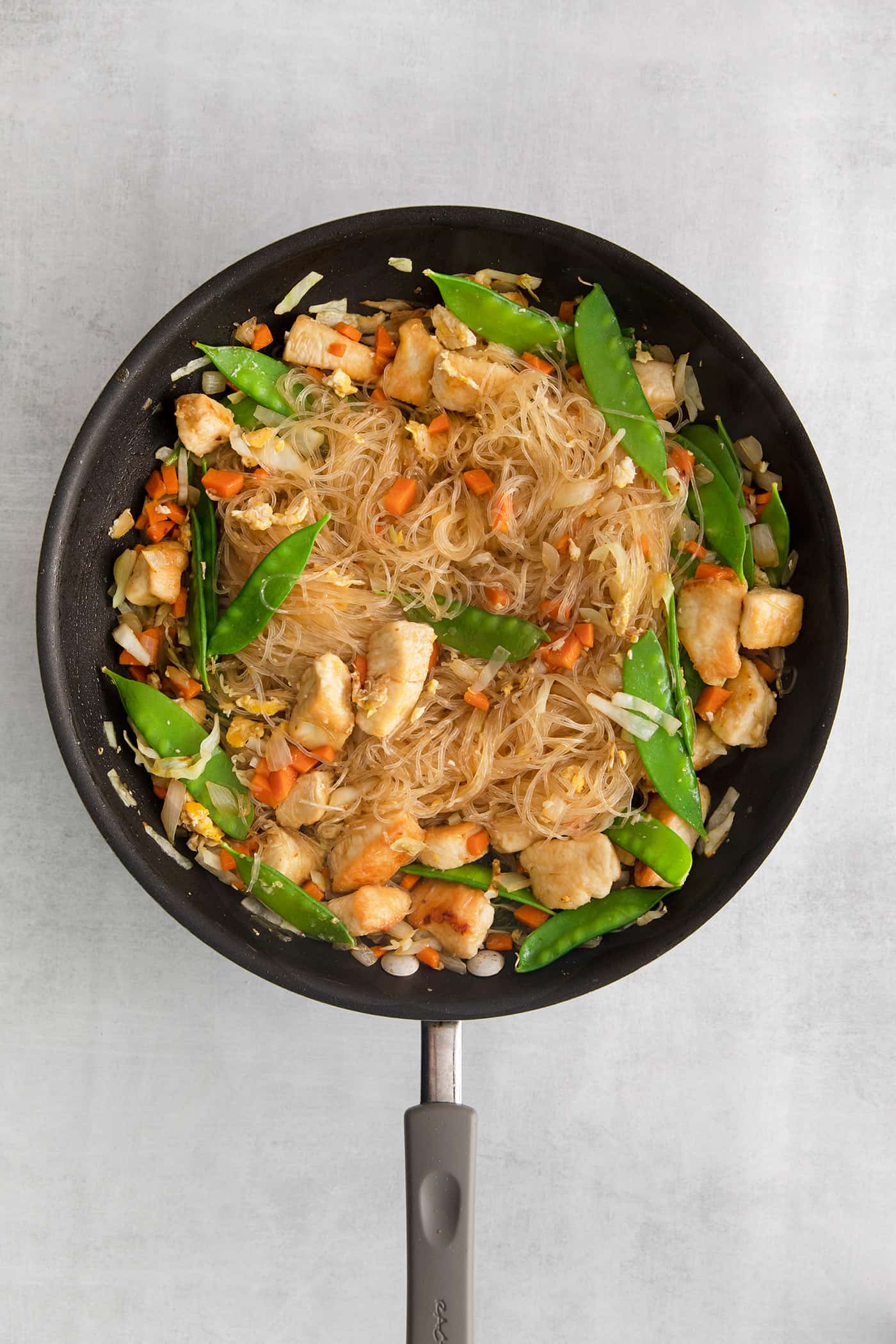 Glass noodle stir fry cooking in a skillet