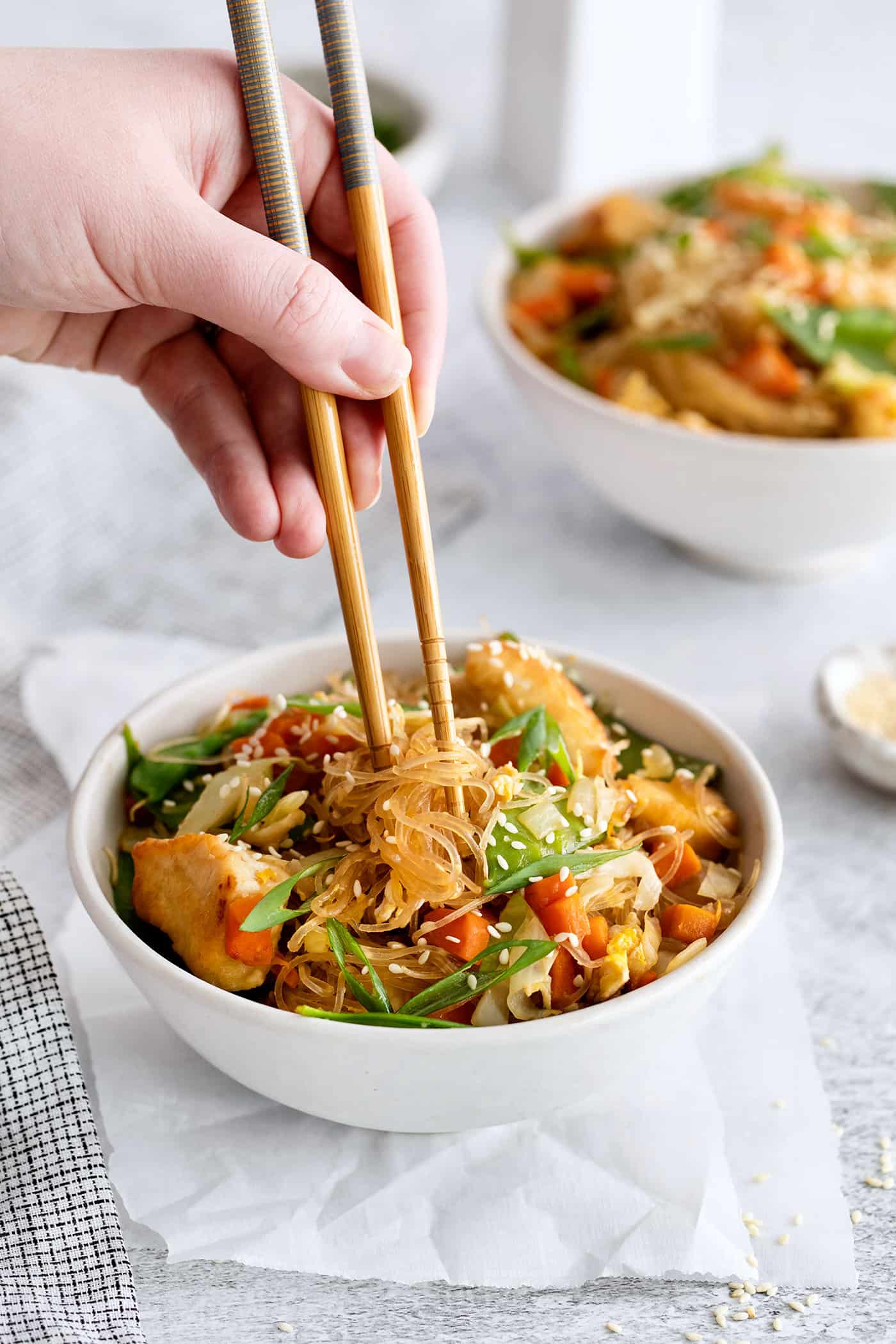 A hand holding chopsticks above pad woon sen