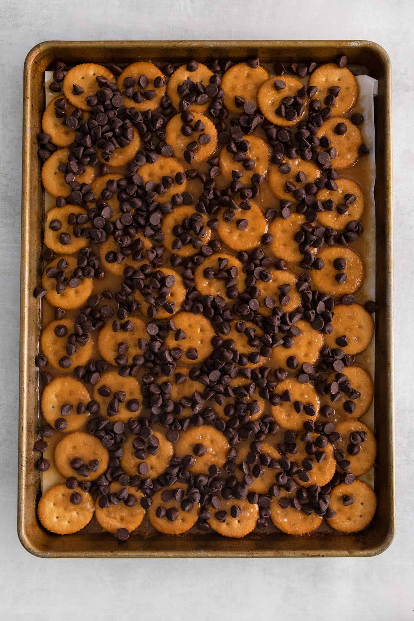 Chocolate chips sprinkled over caramel on ritz crackers