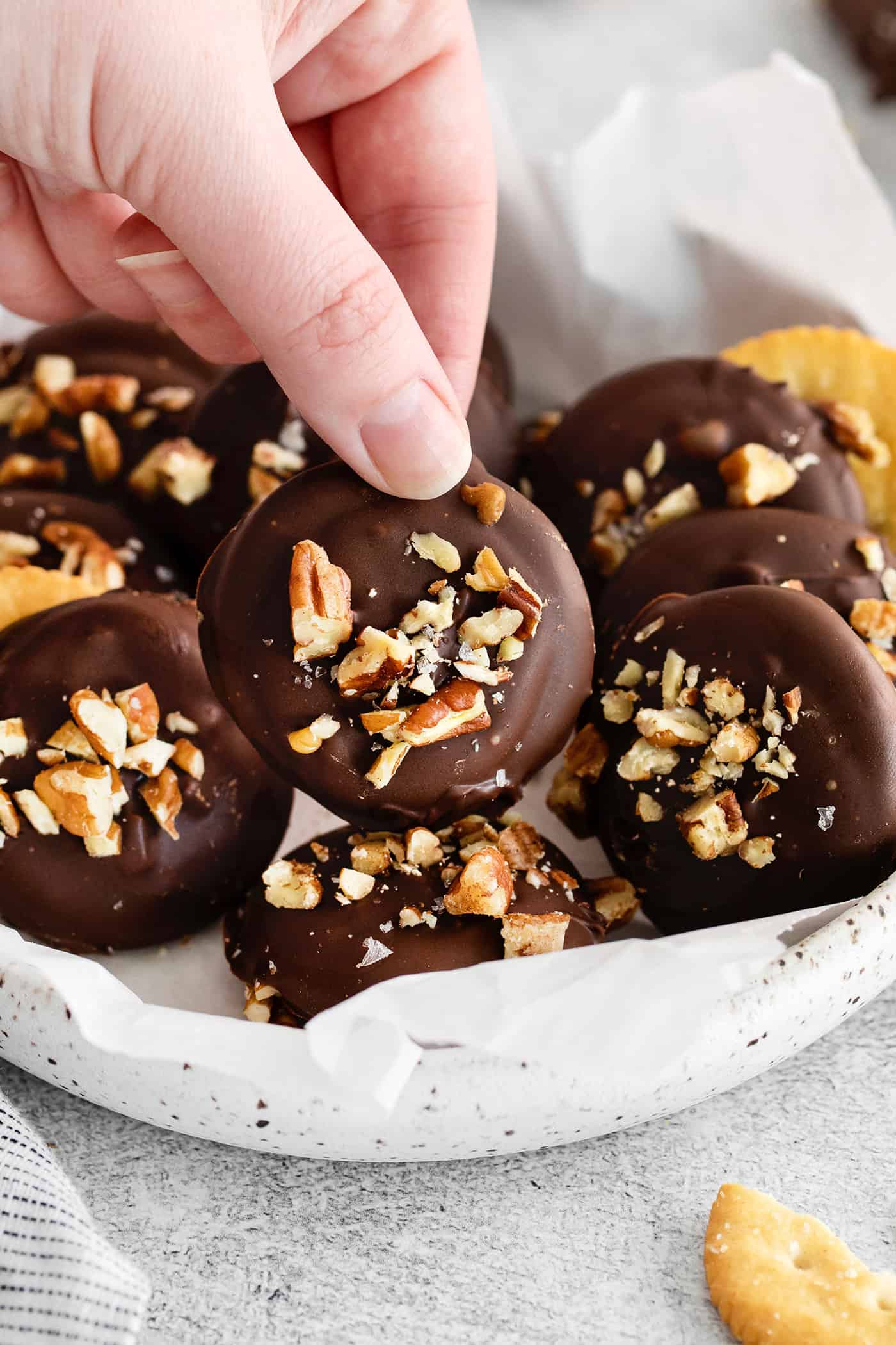 A hand holding a chocolate dipped Ritz cracker