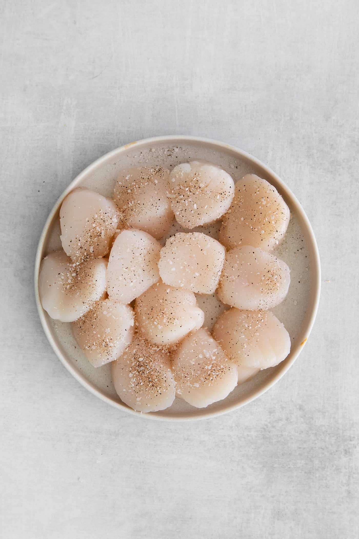 Raw sea scallops on a white plate