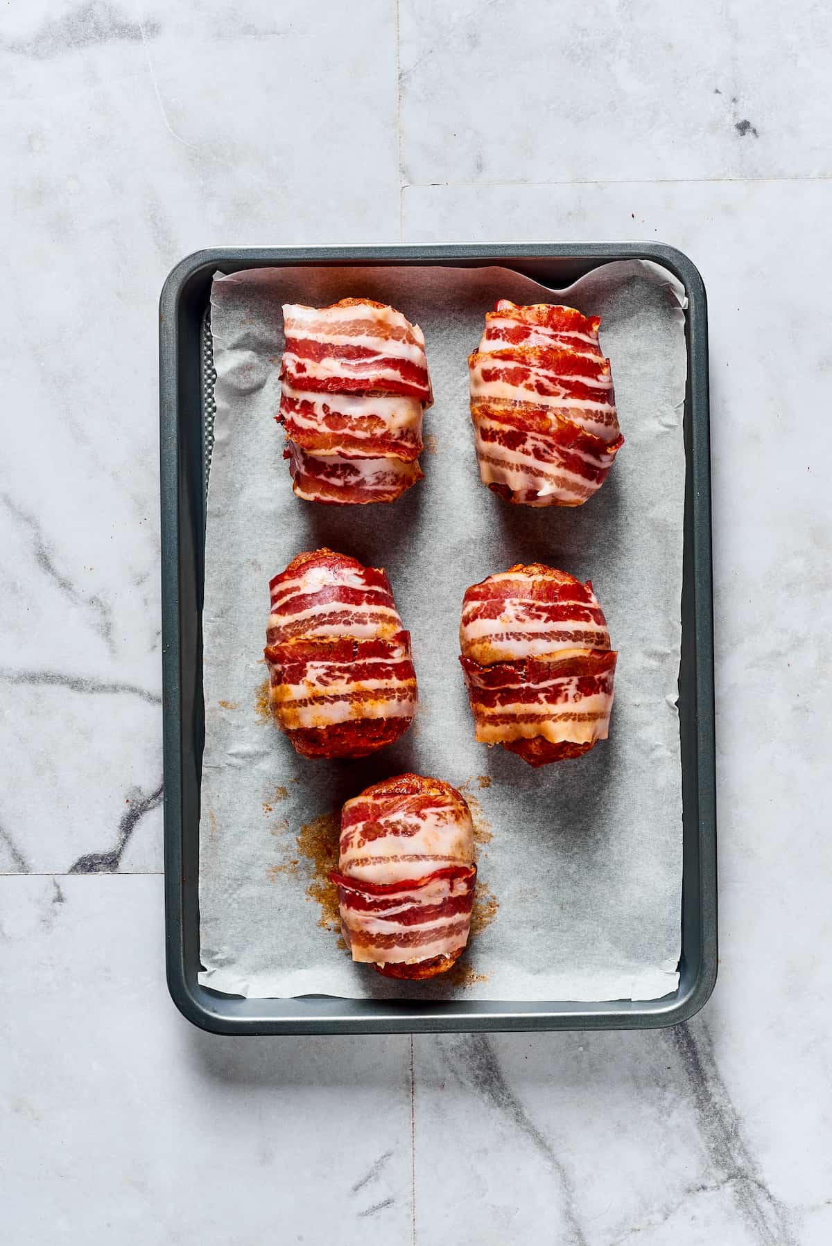 If you love jalapeno poppers, you are going to LOVE these Armadillo Eggs - cheese-stuffed jalapenos wrapped in bacon and sausage. Yum! Armadillo eggs on a baking sheet ready to bake