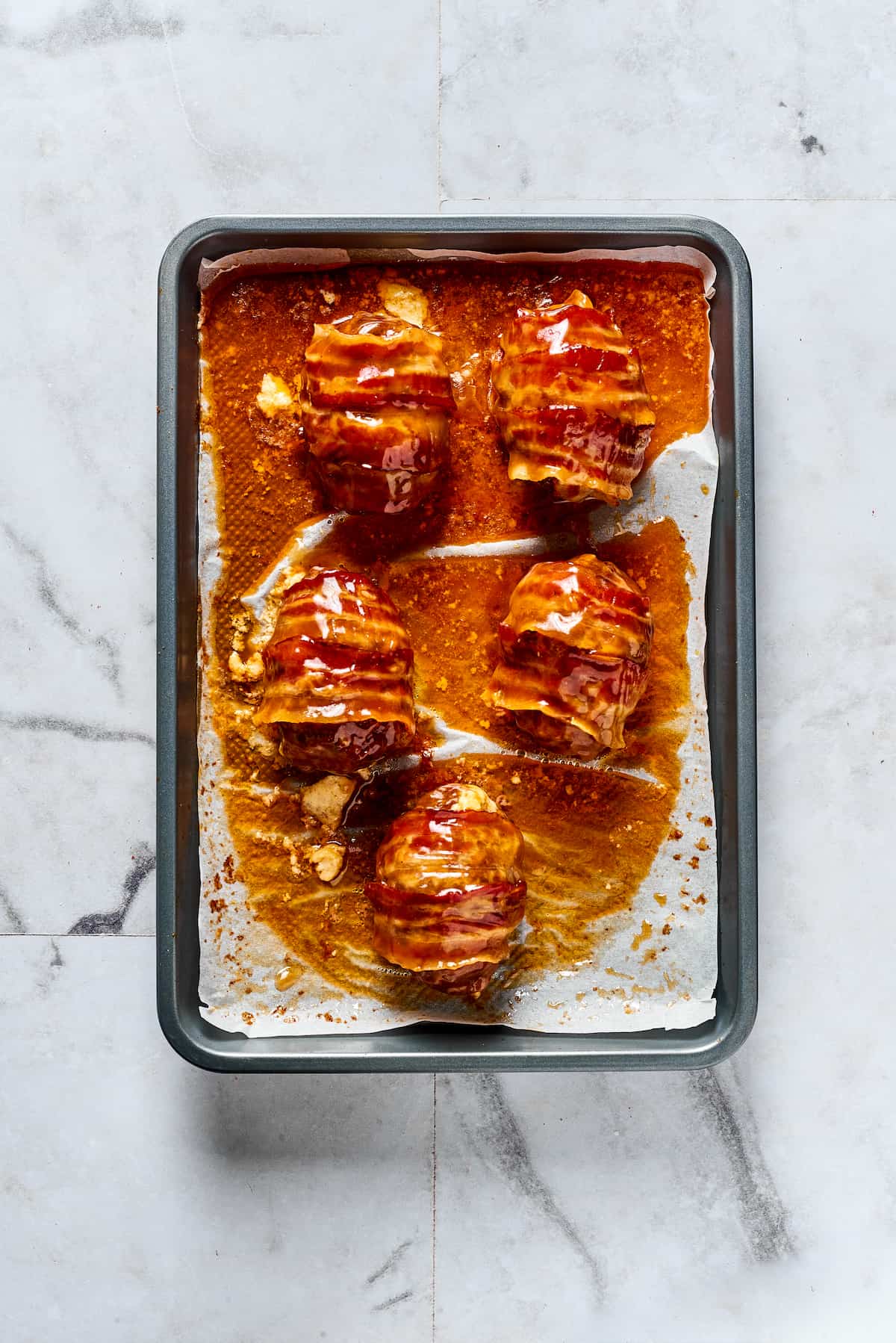 If you love jalapeno poppers, you are going to LOVE these Armadillo Eggs - cheese-stuffed jalapenos wrapped in bacon and sausage. Yum! Armadillo eggs on a baking sheet
