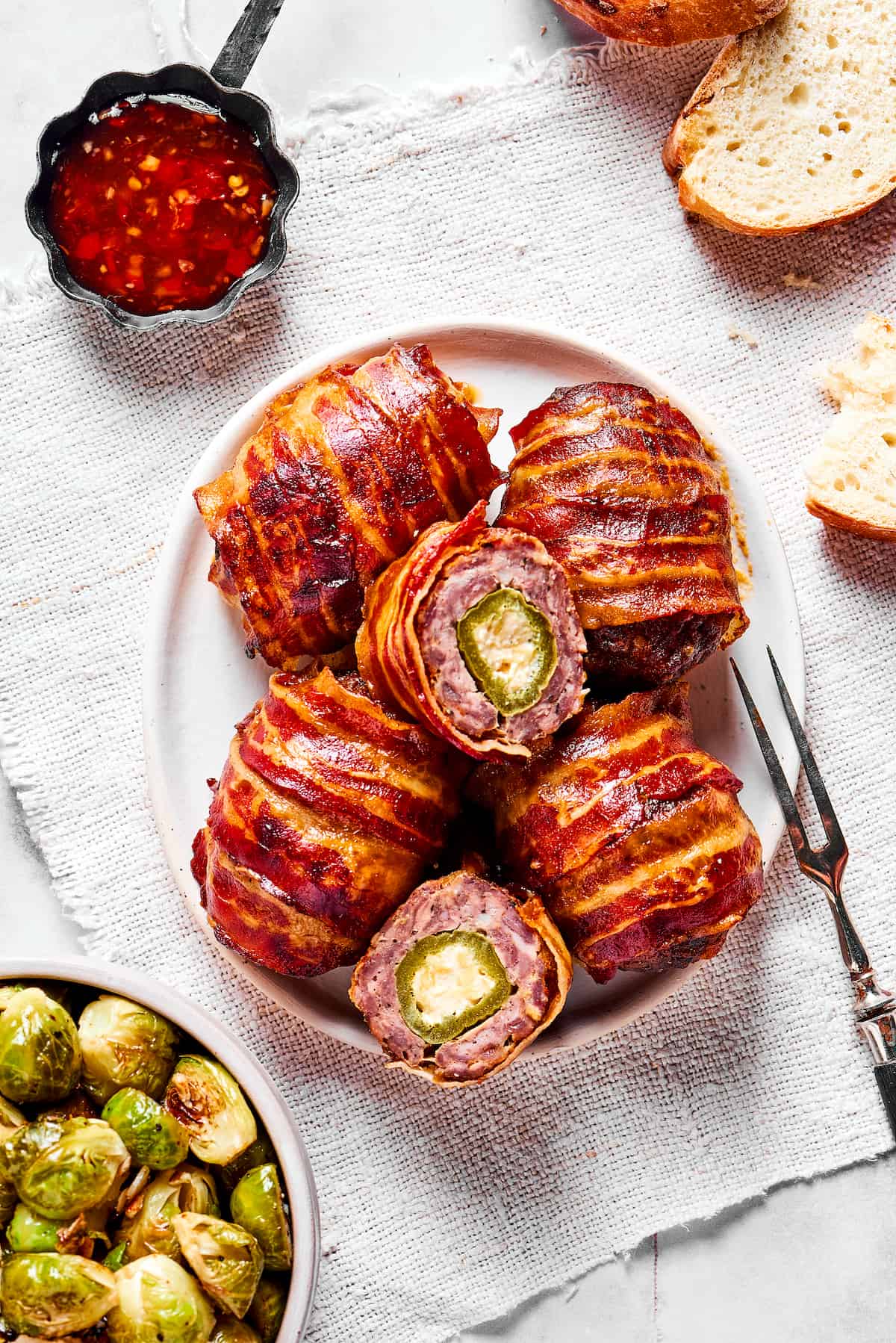 Overhead view of bacon wrapped armadillo eggs on a plate, with one cut in half