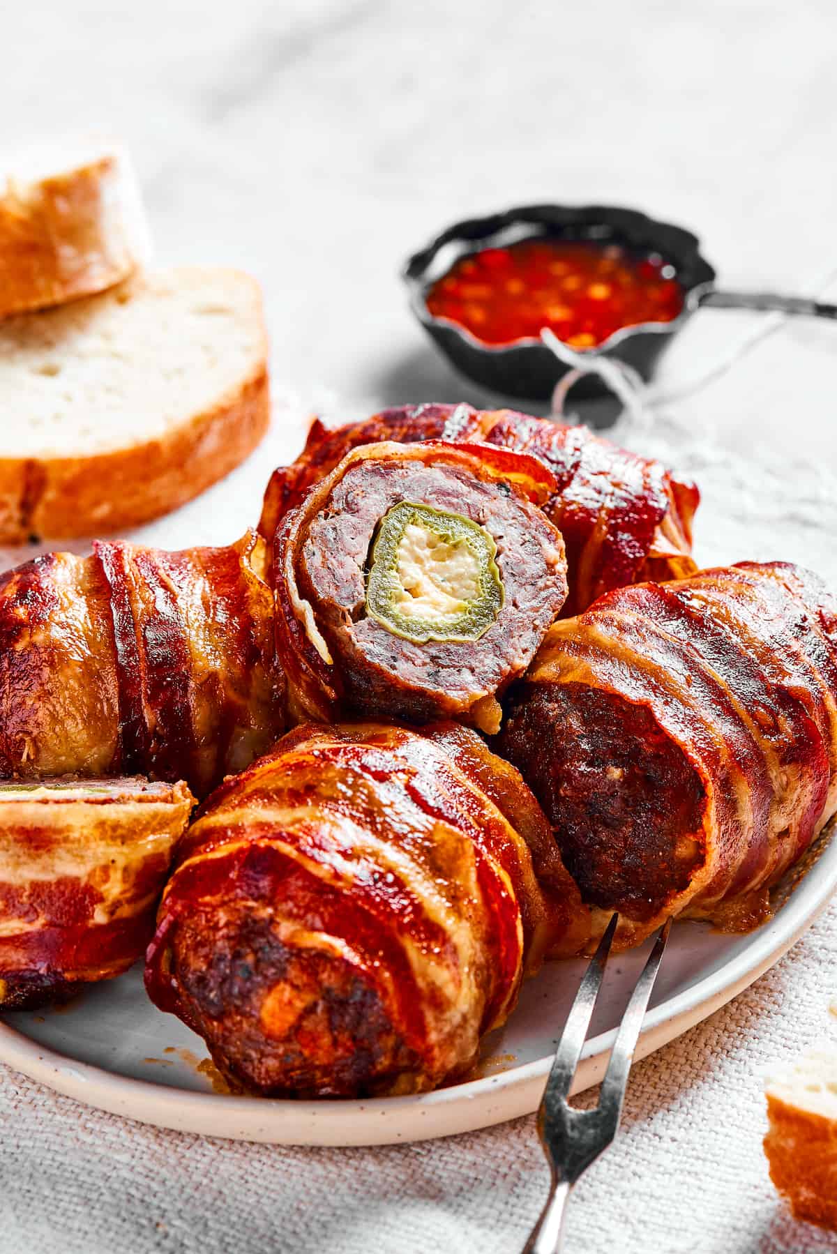 If you love jalapeno poppers, you are going to LOVE these Armadillo Eggs - cheese-stuffed jalapenos wrapped in bacon and sausage. Yum! Texas wrapped armadillo eggs on a white plate