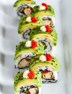 overhead photo of sushi roll topped with thin slices of avocado