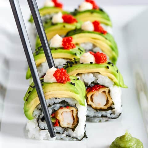 chopsticks picking up a piece of sushi roll
