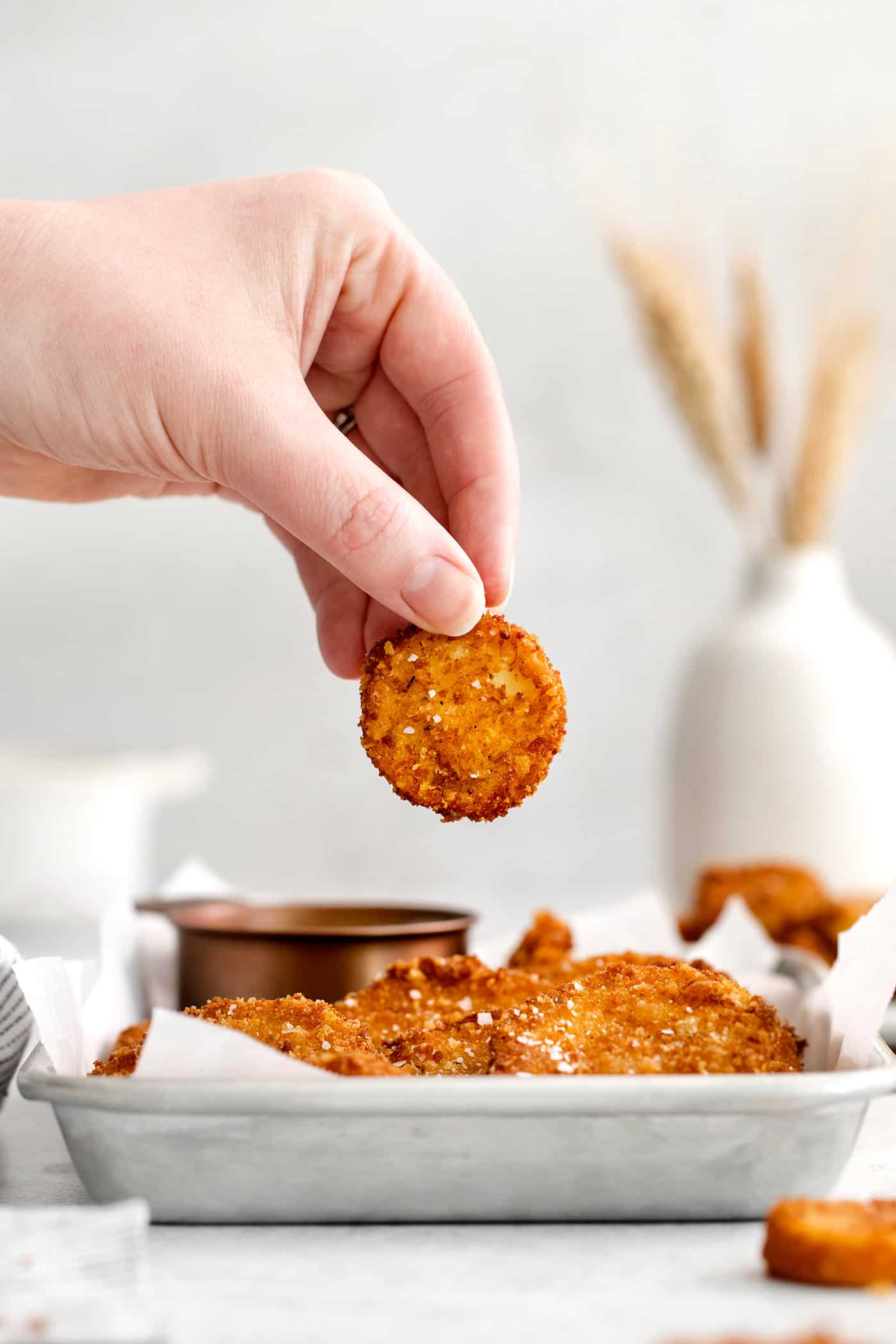 A hand holding a round of fried squash