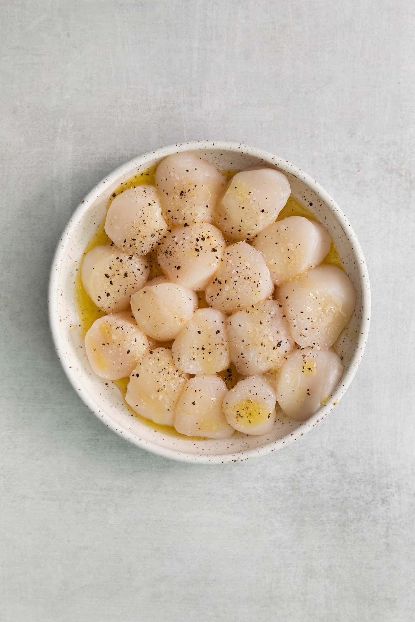 Scallops in a bowl with butter, salt, and pepper