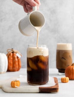 A hand pouring cold foam over cold brew