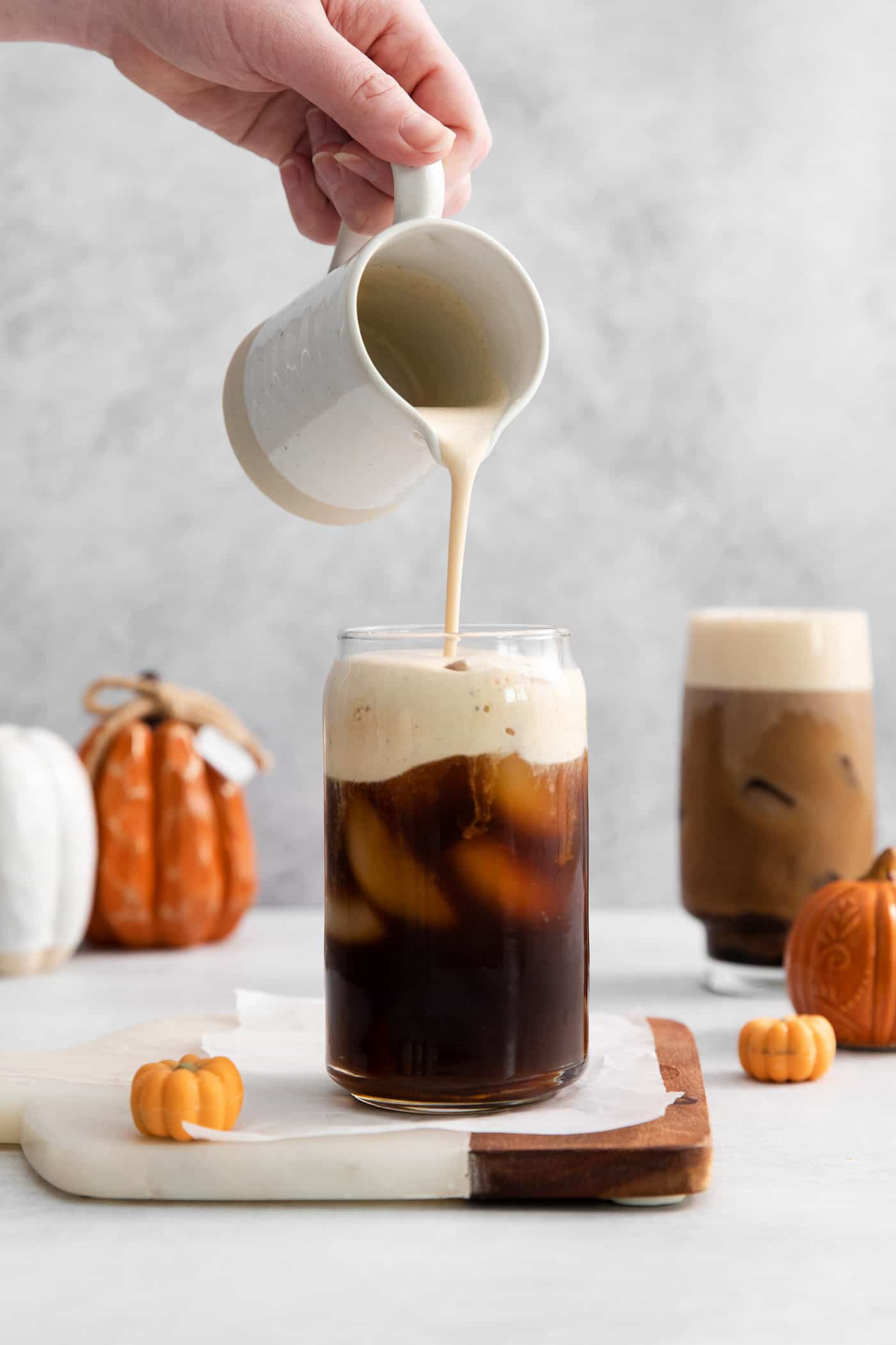 A hand pouring cold foam over cold brew