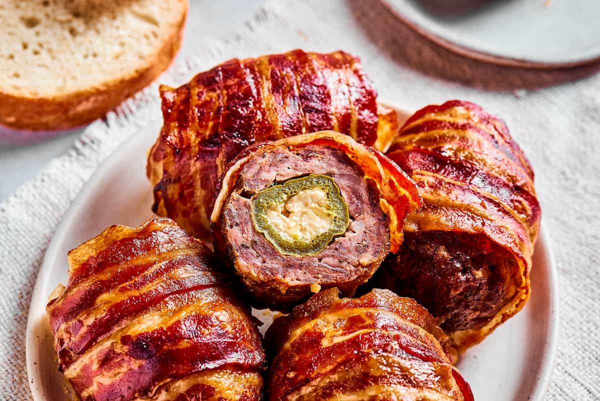 a plate of armadillo eggs, with one cut open to reveal the stuffed jalapeno inside