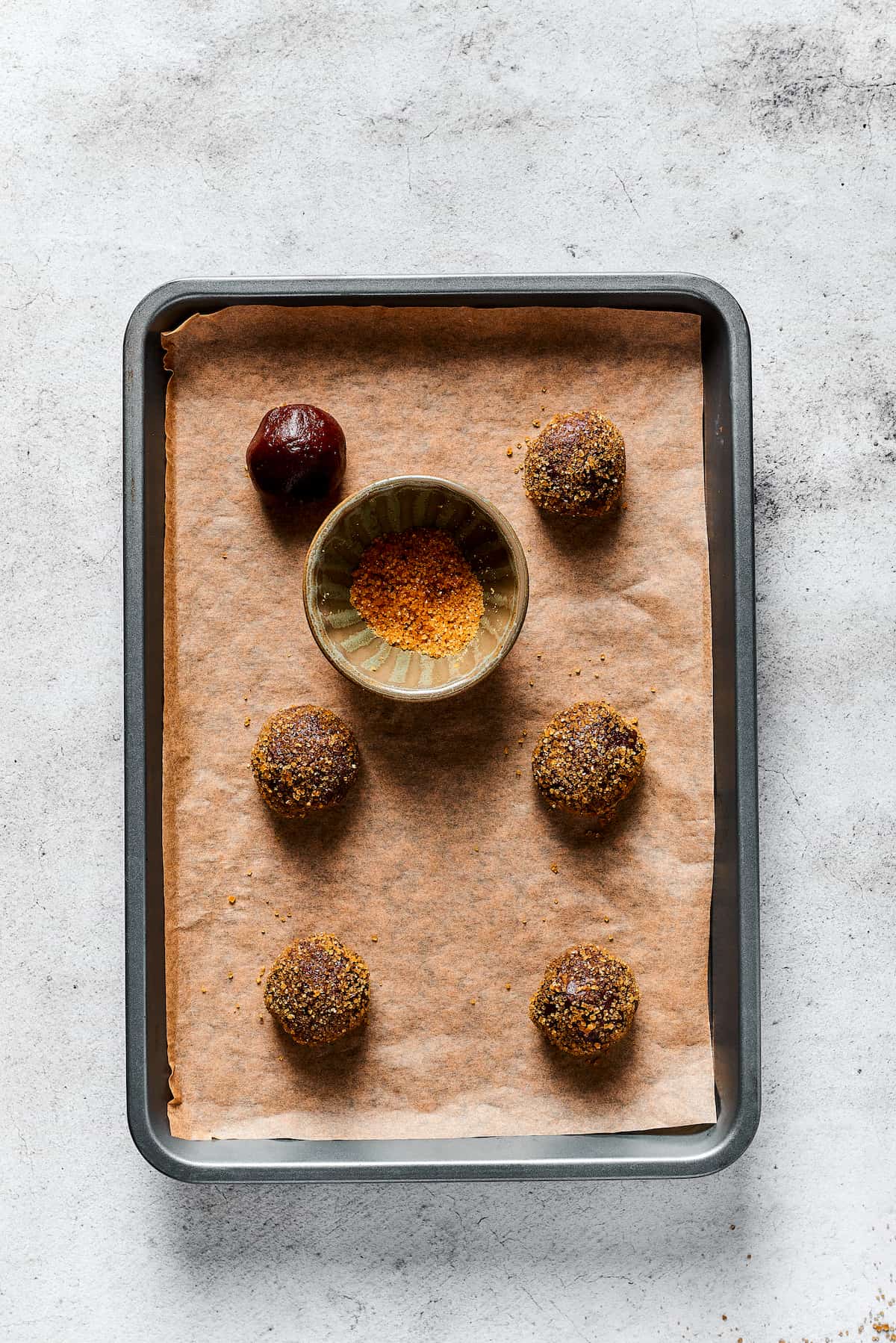 Chocolate cookie dough balls rolled in sugar on a baking sheet