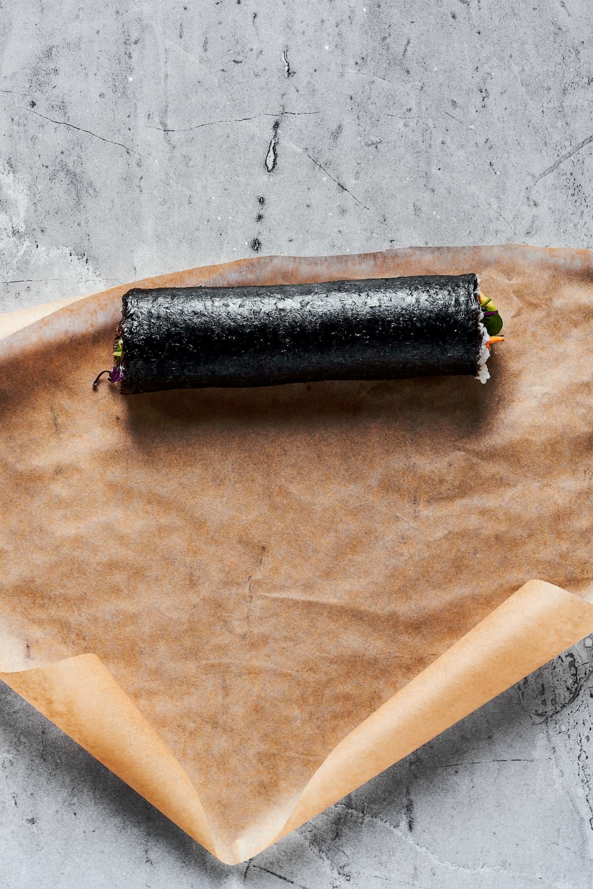 Overhead view of a sushi burrito on brown paper