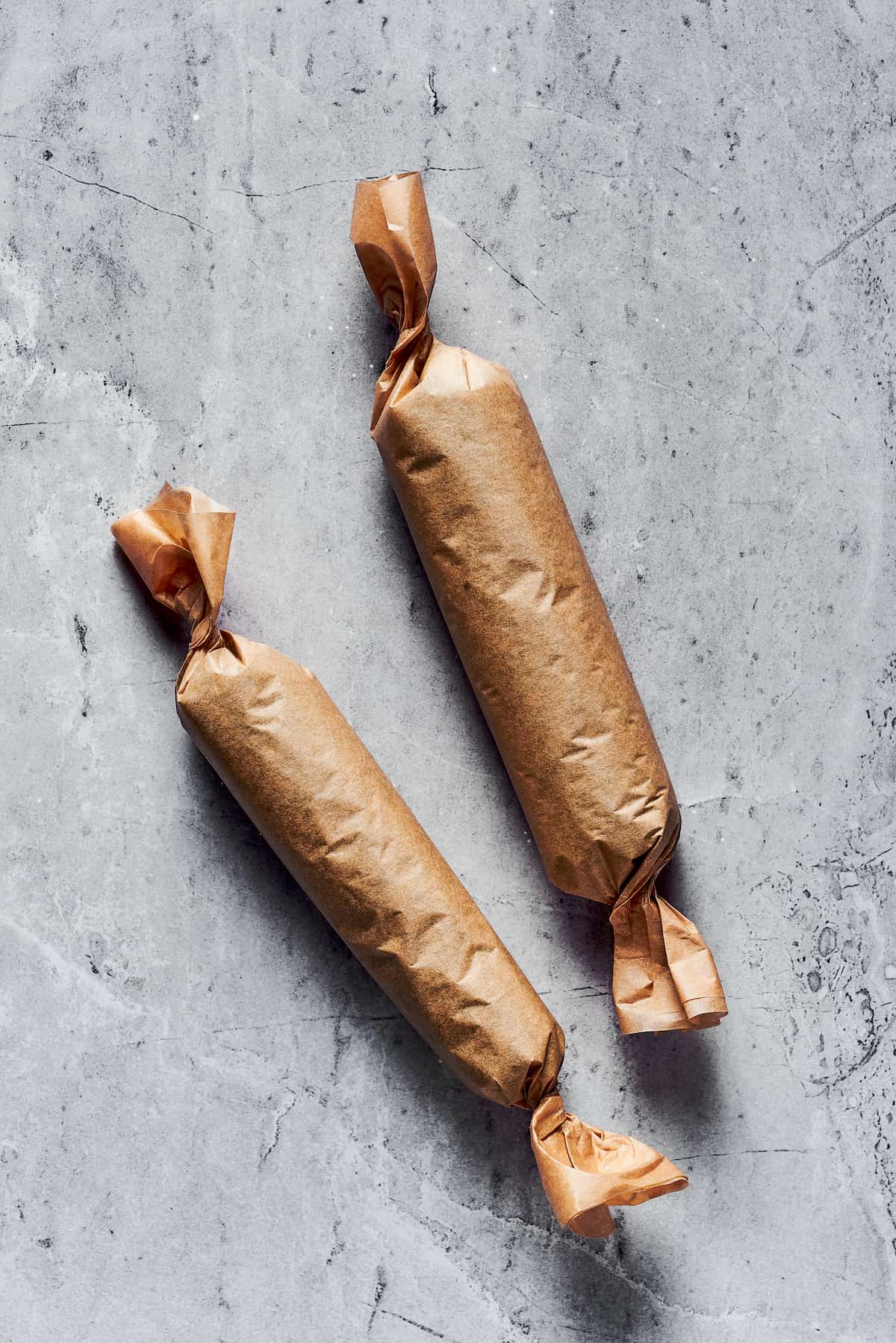 Two sushi burritos wrapped in brown paper