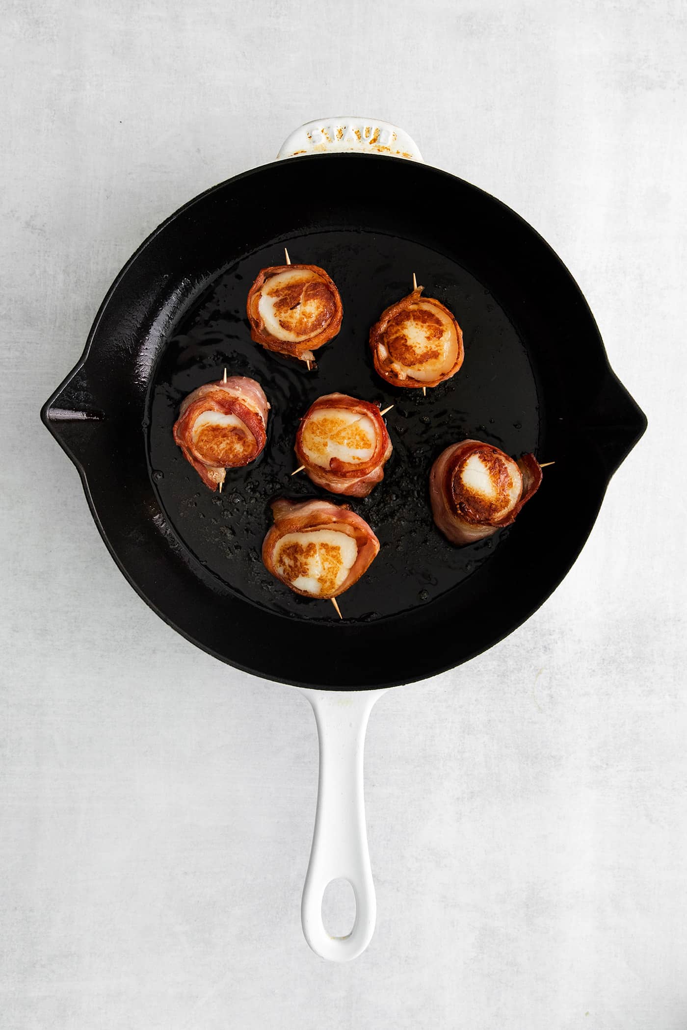 Bacon wrapped scallops in a skillet