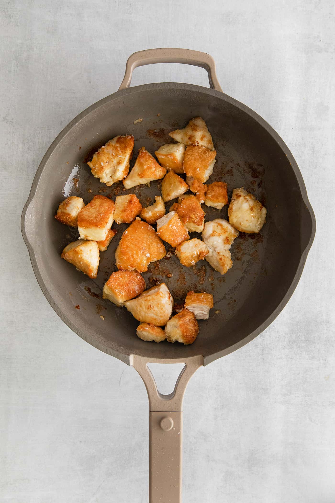 Chunks of chicken sauteing in a skillet