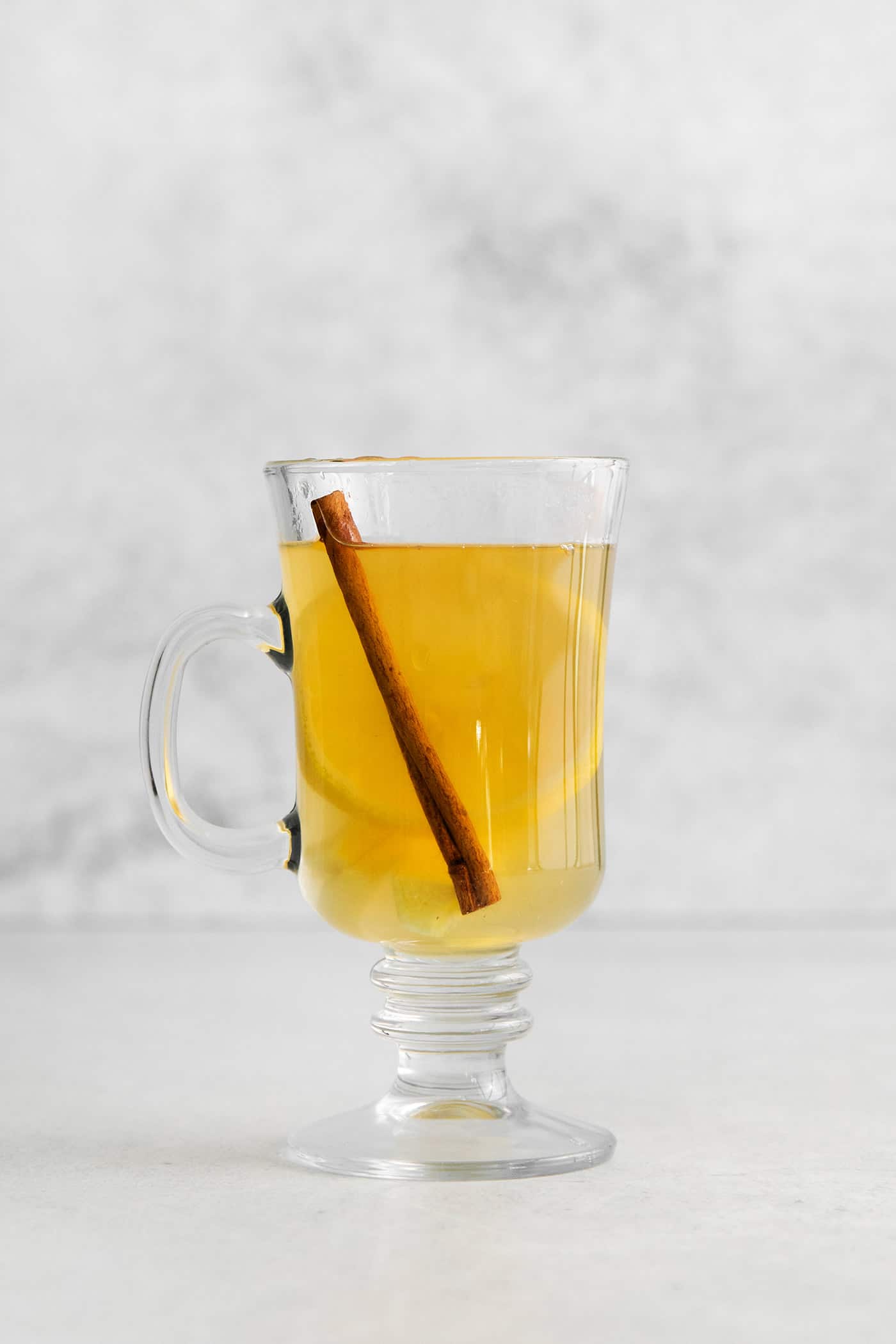 A hot tottie in a glass mug with a cinnamon stick