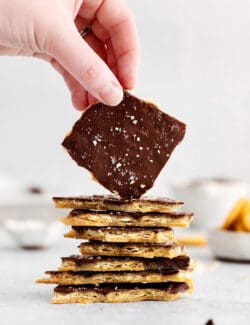 a stack of Ritz cracker toffee, with a hand holding up a piece