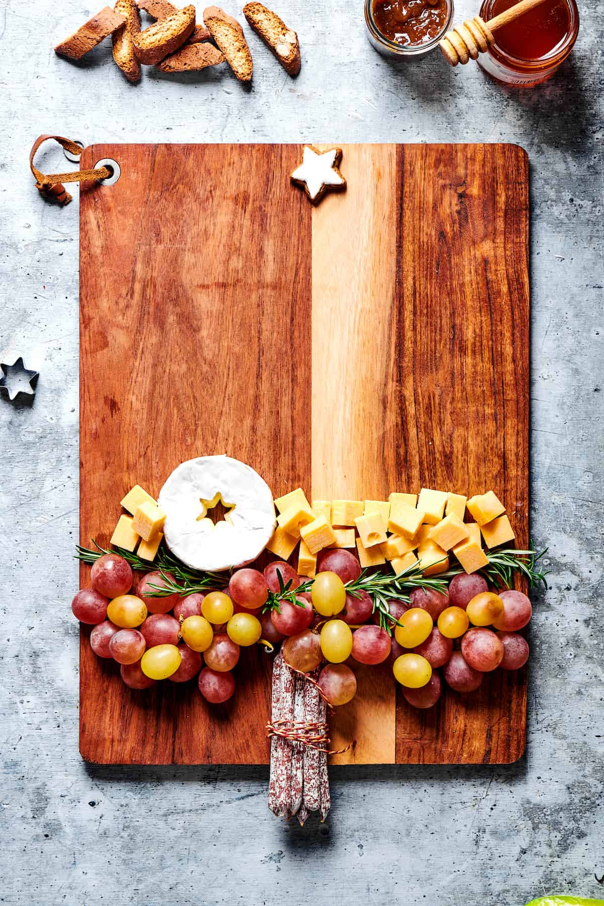 Grapes, rosemary, and chunks of cheese on a cutting board