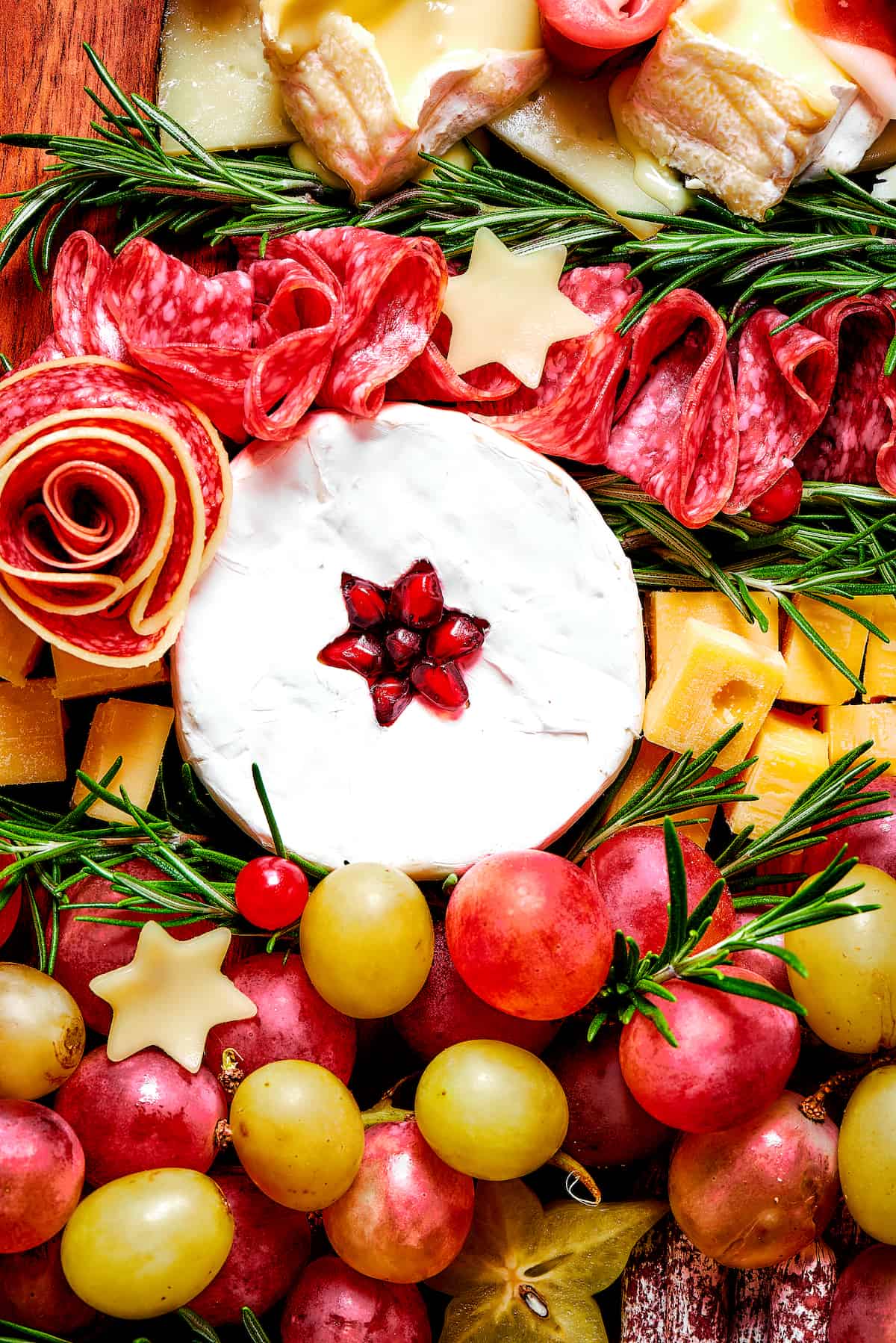 Close-up of cheese, grapes, cured meats, and rosemary