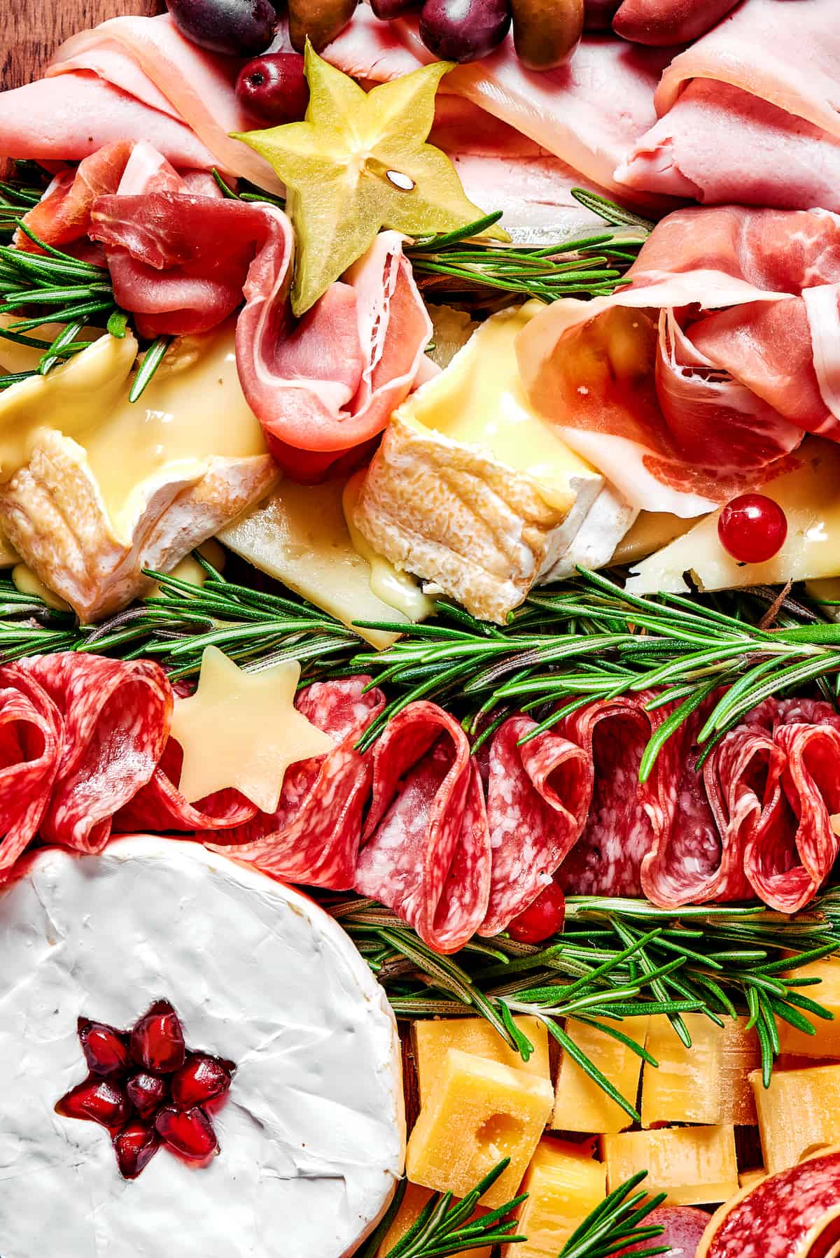 Close up of a holiday charcuterie board with salami, rosemary, and cheese
