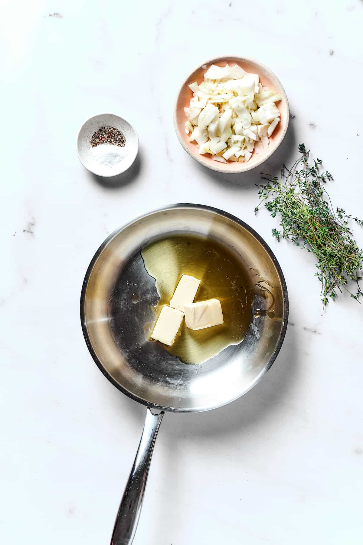 Overhead view of butter melting in a pan with olive oil