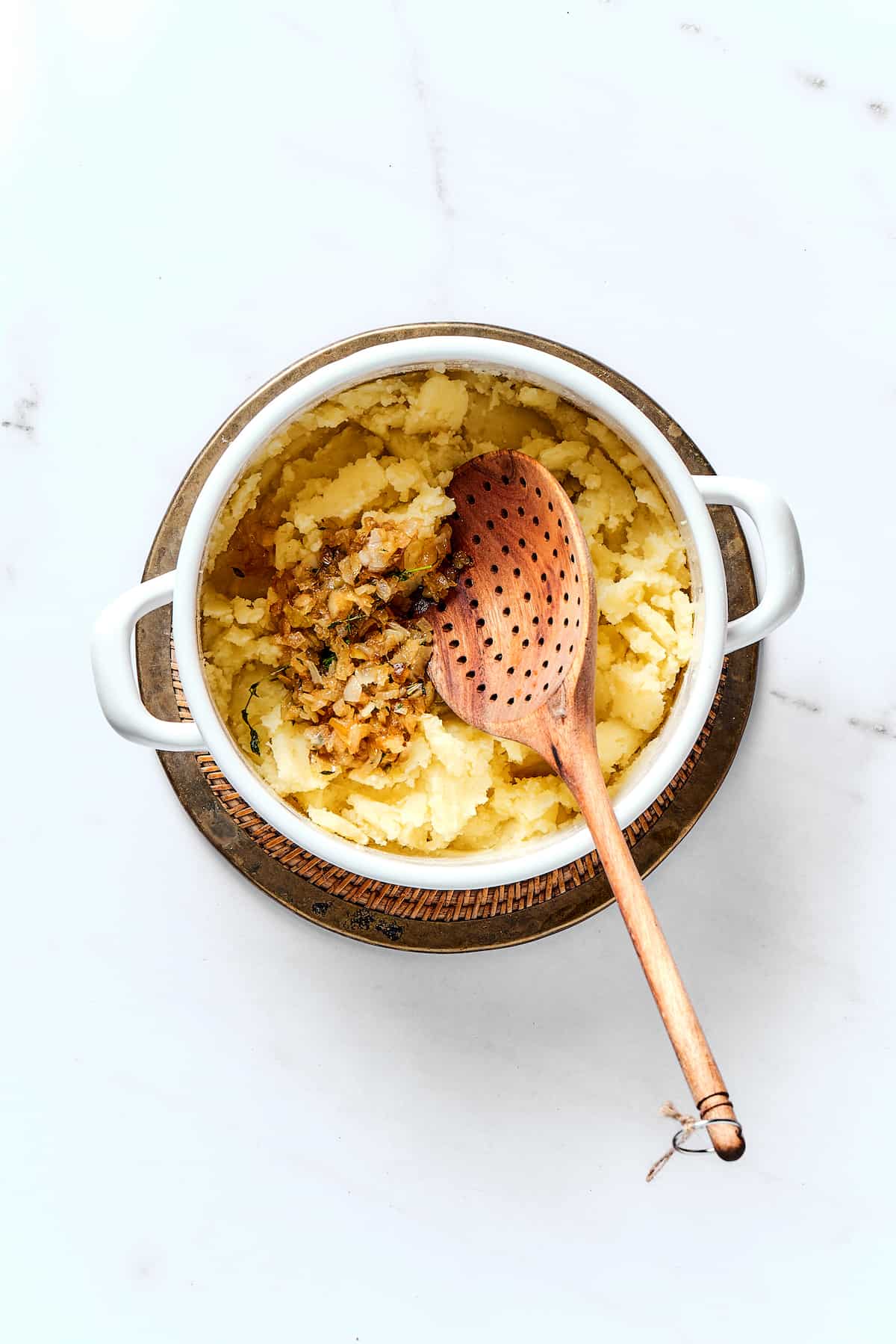 A wooden spoon mashing potatoes