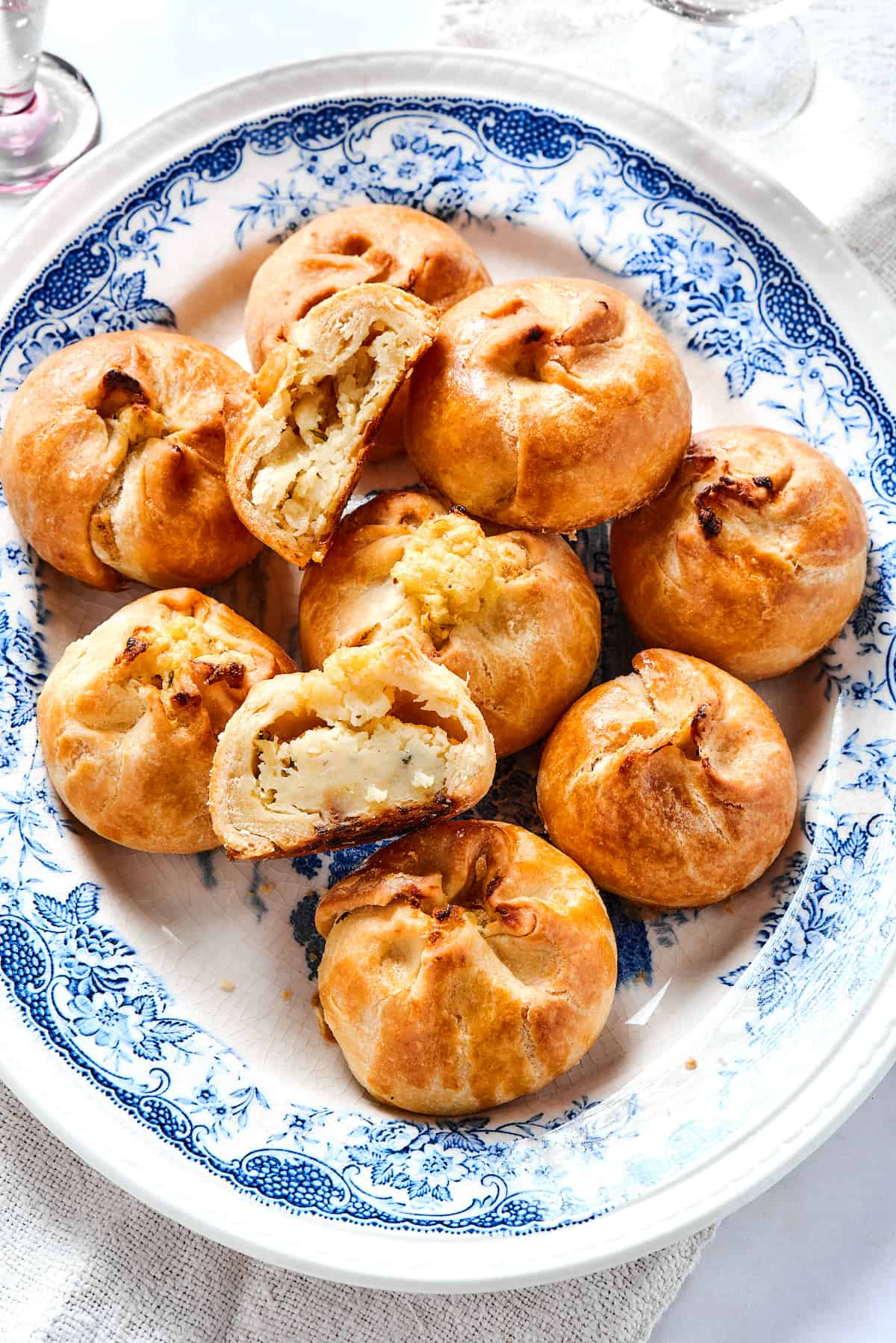 Overhead view of a plate of potato knishes, with one cut in half