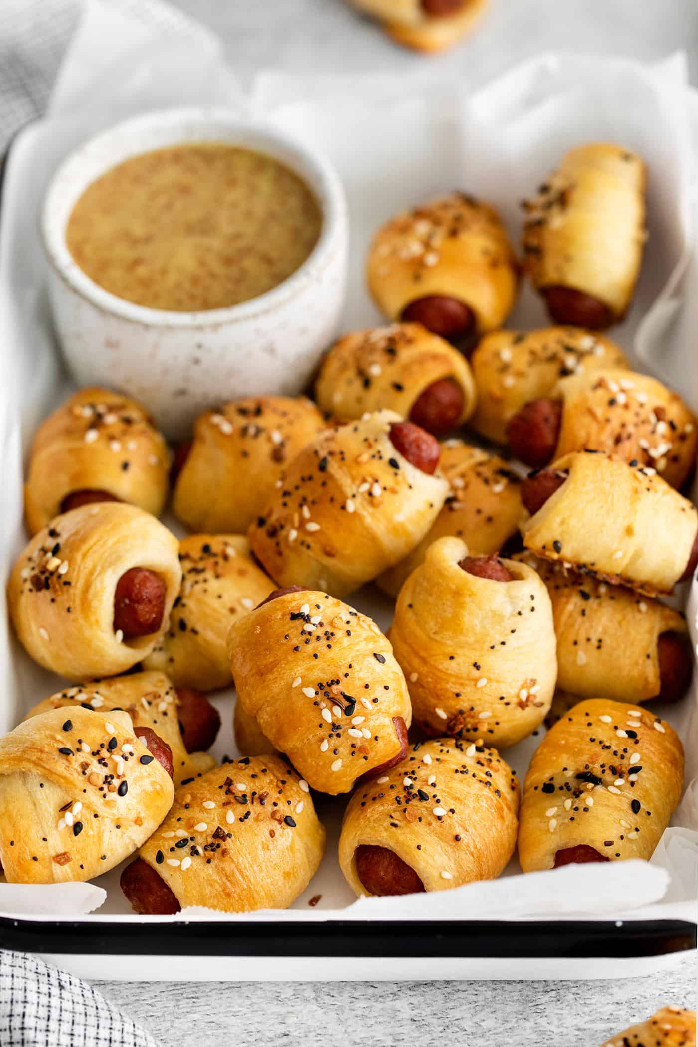 Everything Bagel Pigs in a Blanket are the perfect appetizer– mini sausage wrapped in crescent dough, topped with everything bagel seasoning Overhead view of everything bagel pigs in a blanket in a tray