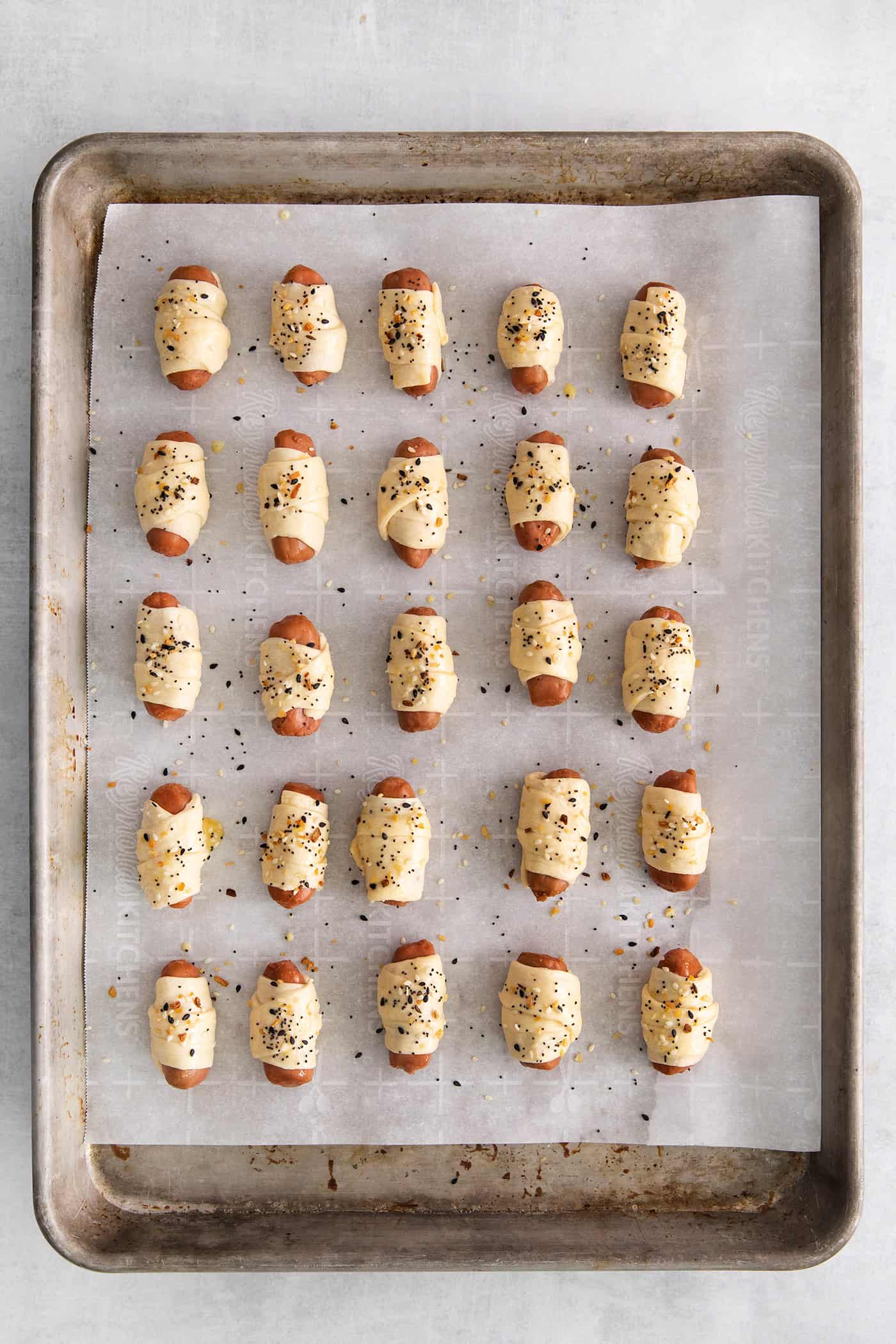 Overhead view of mini sausages wrapped in crescent dough and topped with everything bagel seasoning