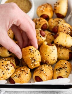 A hand grabbing a mini pigs in a blanket