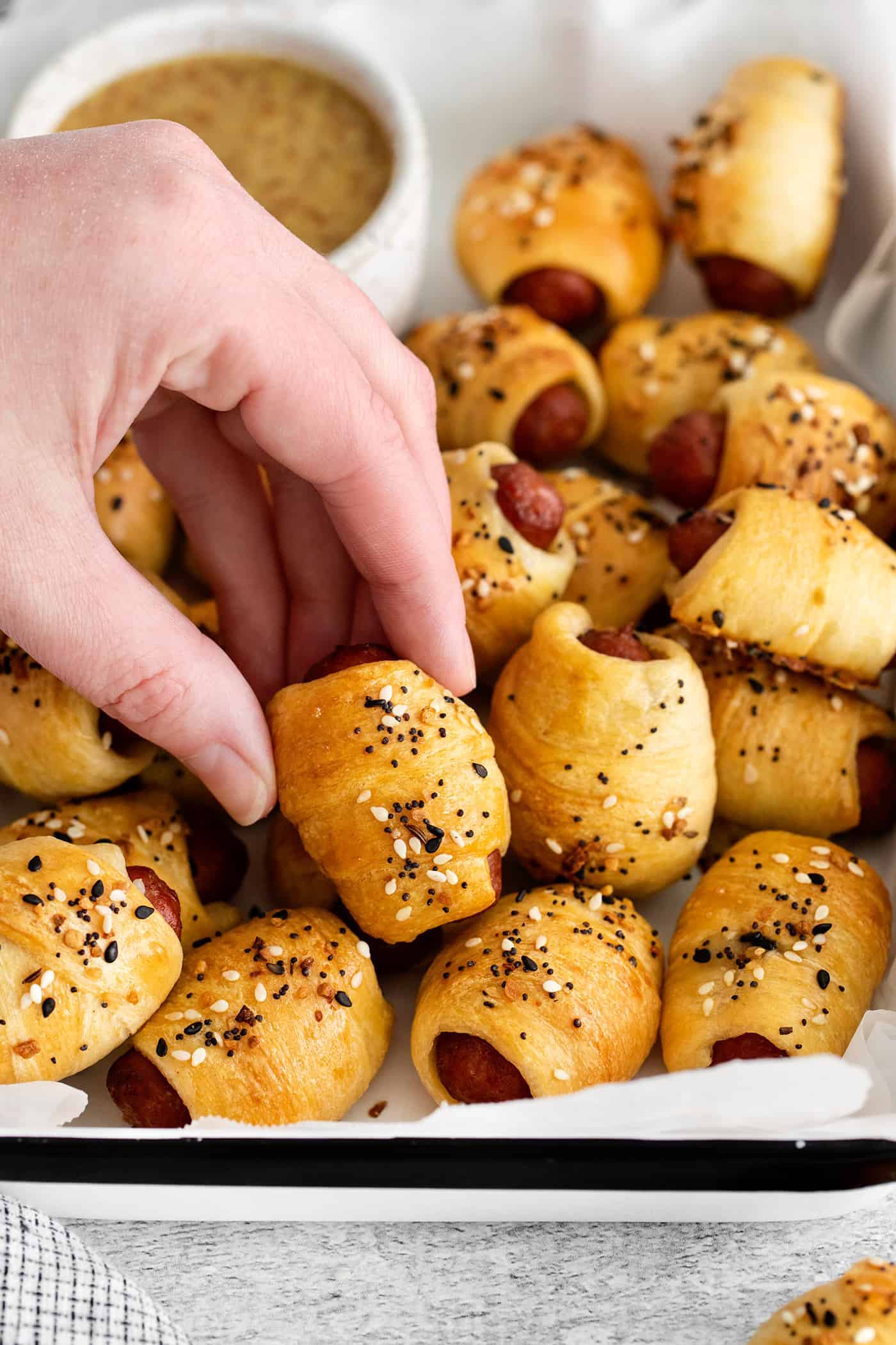 A hand grabbing a mini pigs in a blanket