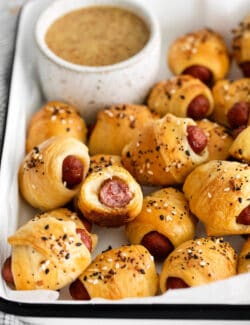 Mini pigs in a blanket on a tray, one cut in half