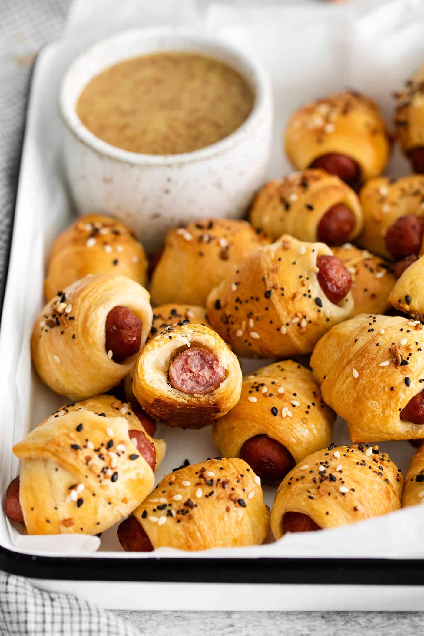 Mini pigs in a blanket on a tray, one cut in half