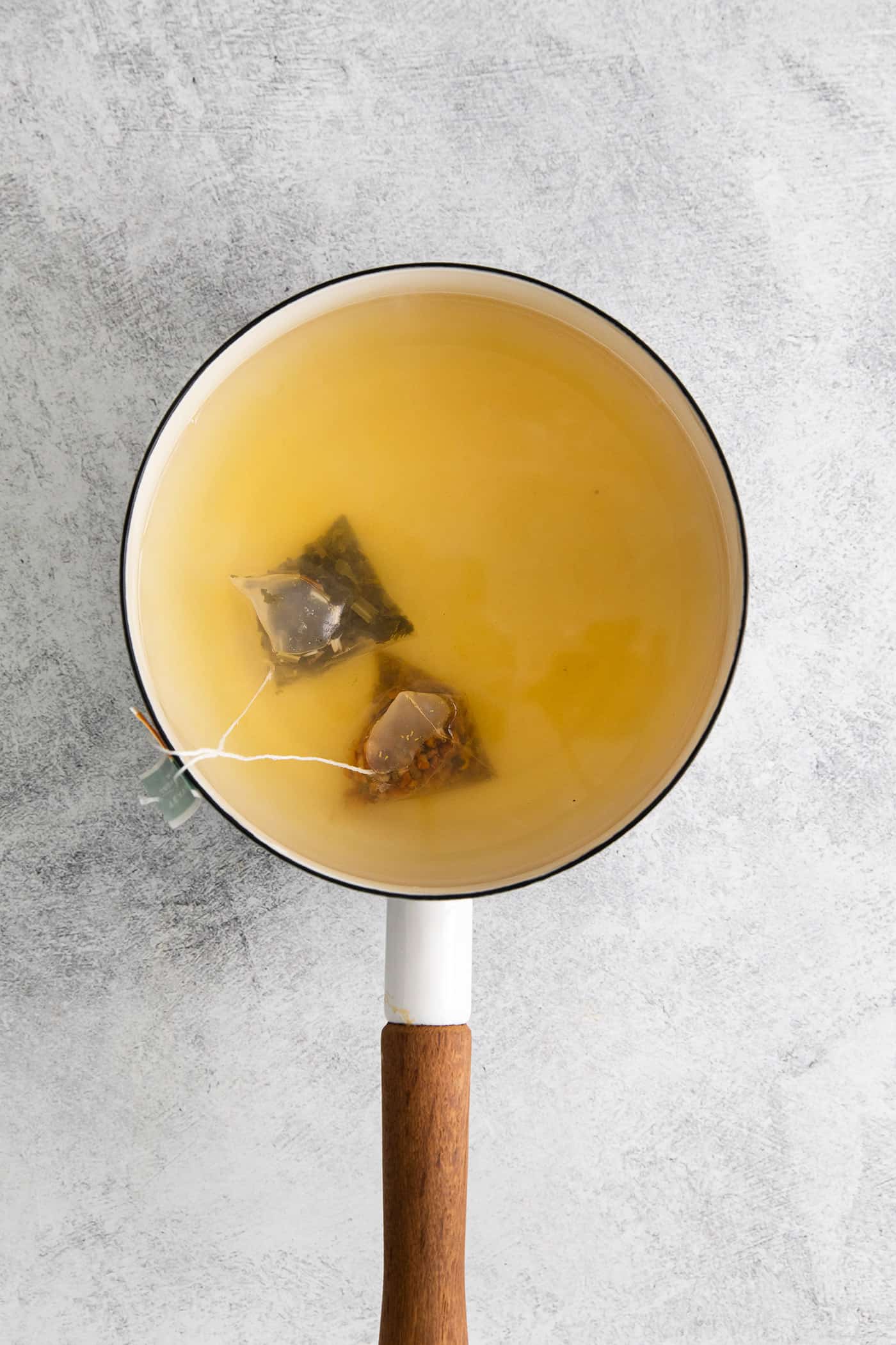 Two tea bags steeping in a saucepan of water