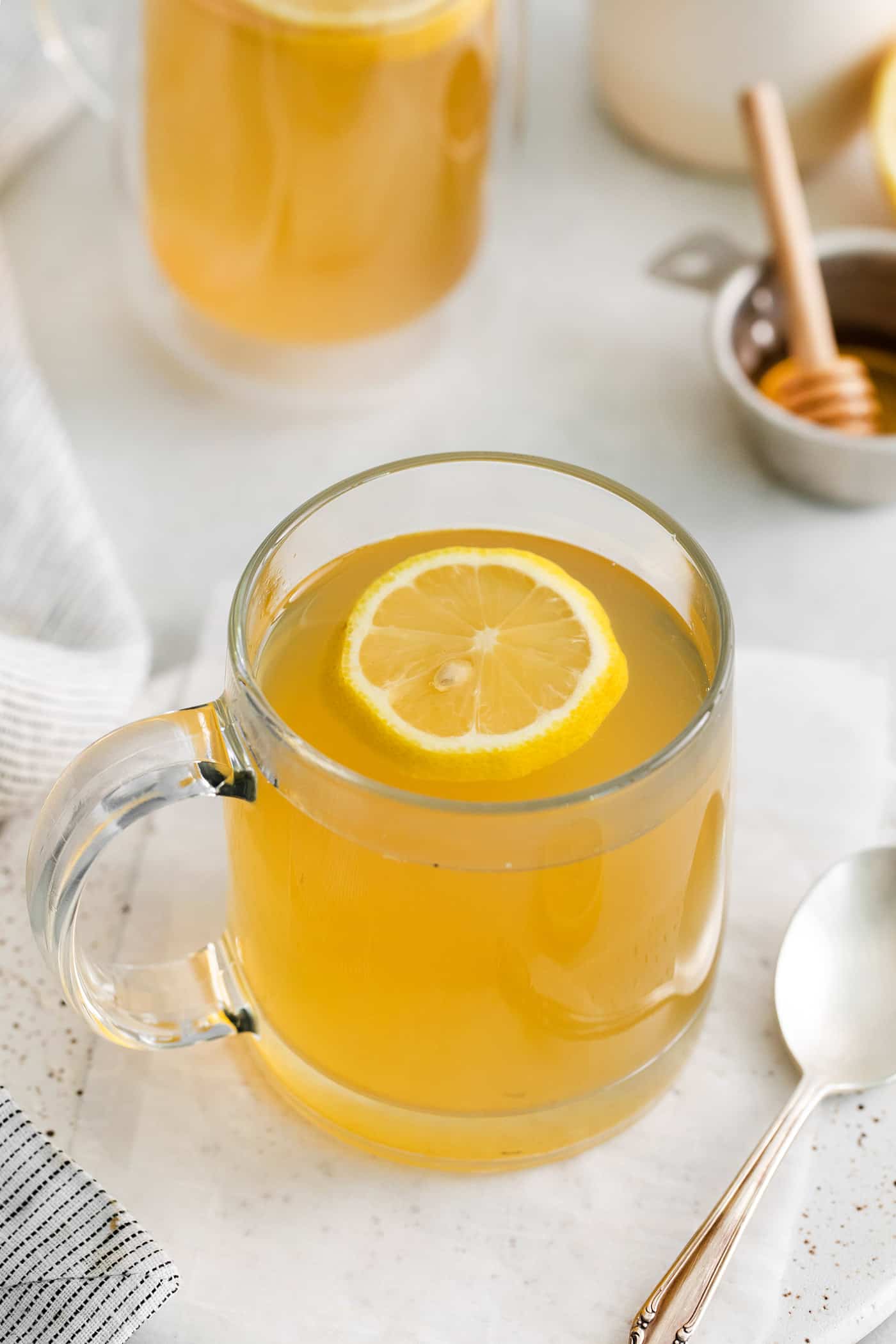 Angled view of a mug of honey citrus mint tea with a slice of lemon