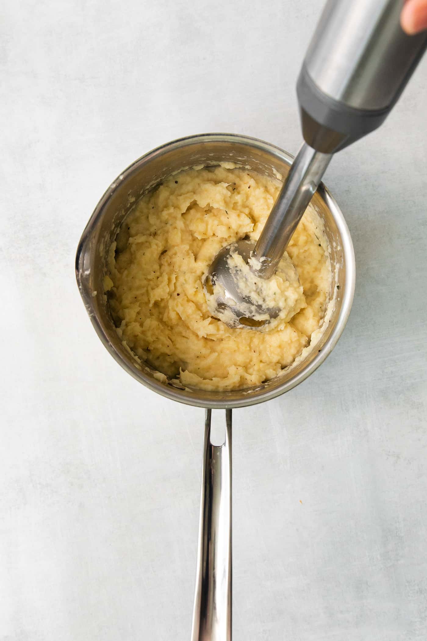 An immersion blender mashing boiled parsnip