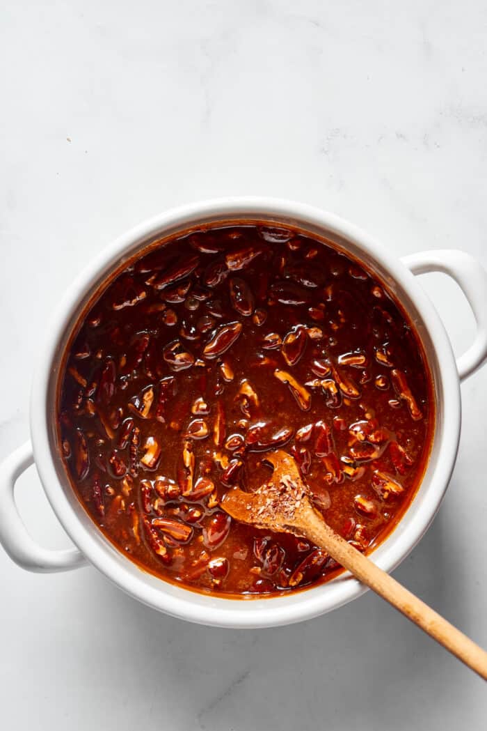 A wooden spoon stirring a pecan praline mixture