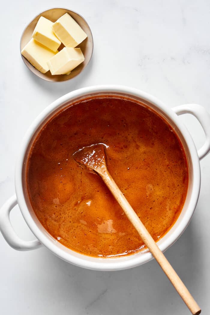 A wooden spoon stirring a candy mixture in a pot