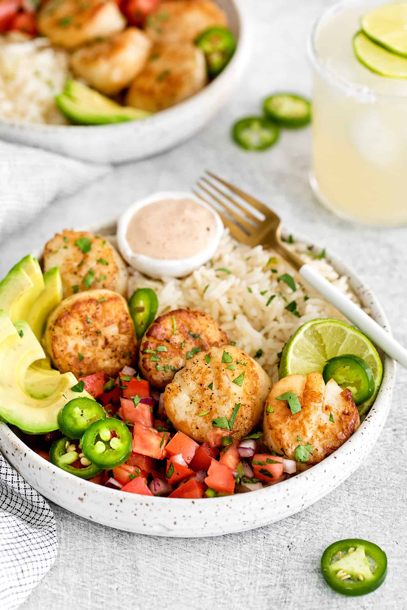 A rice bowl with scallops, pico de gallo, avocado, and lime crema