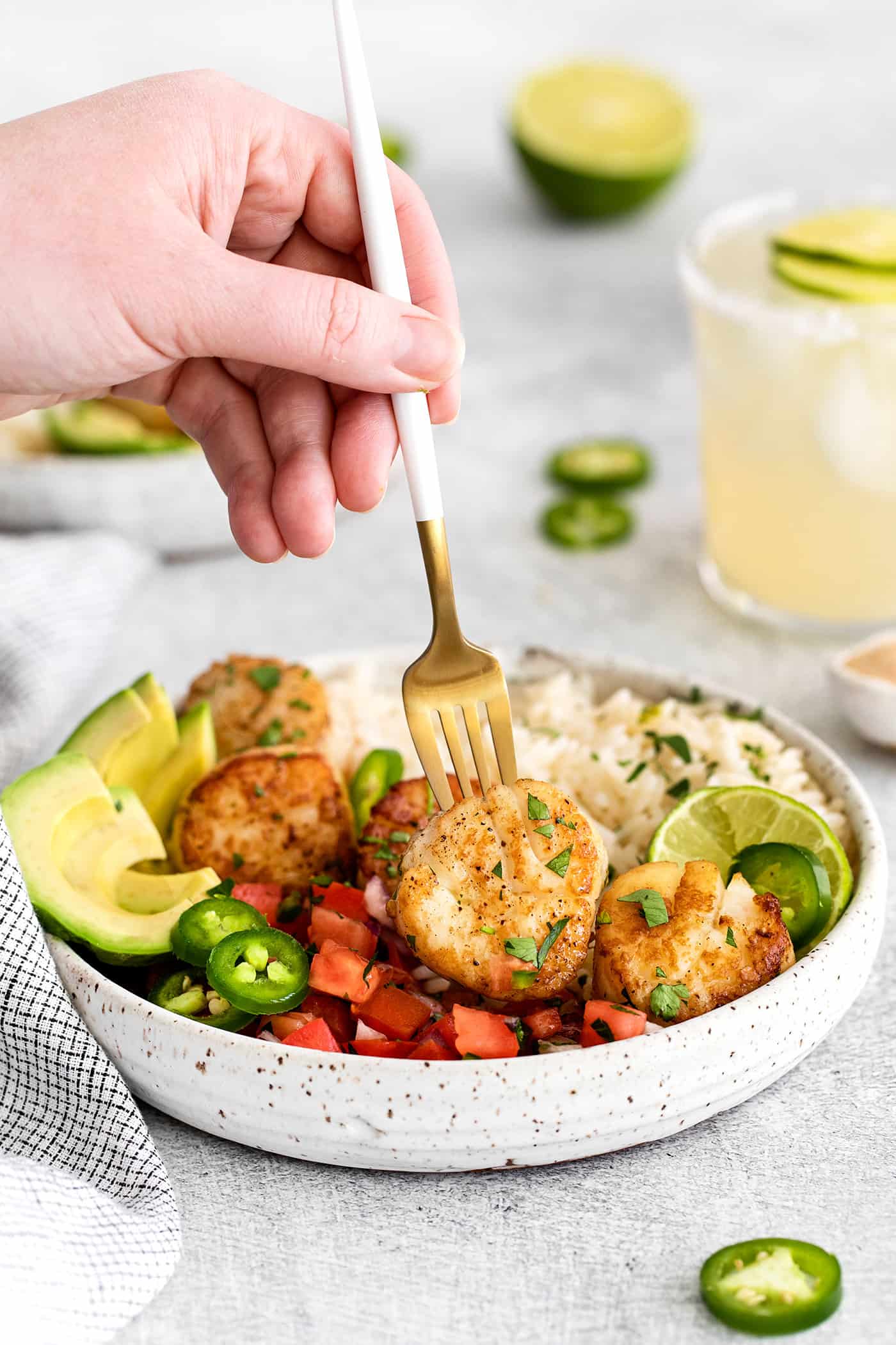 A fork spearing a scallop in a rice bowl