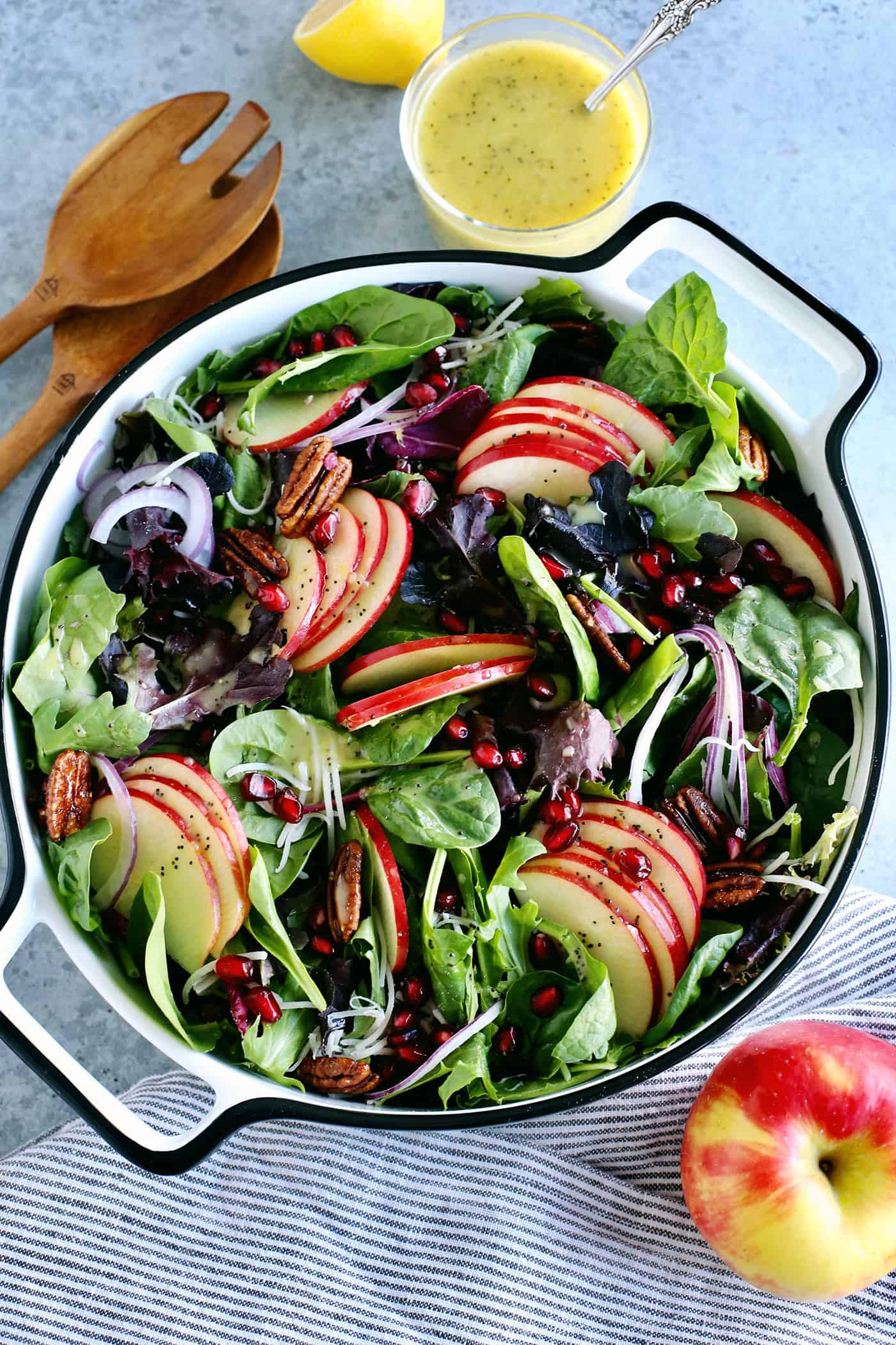 a large bowl of fresh salad greens, sliced apples, pecans, and pomegranate arils