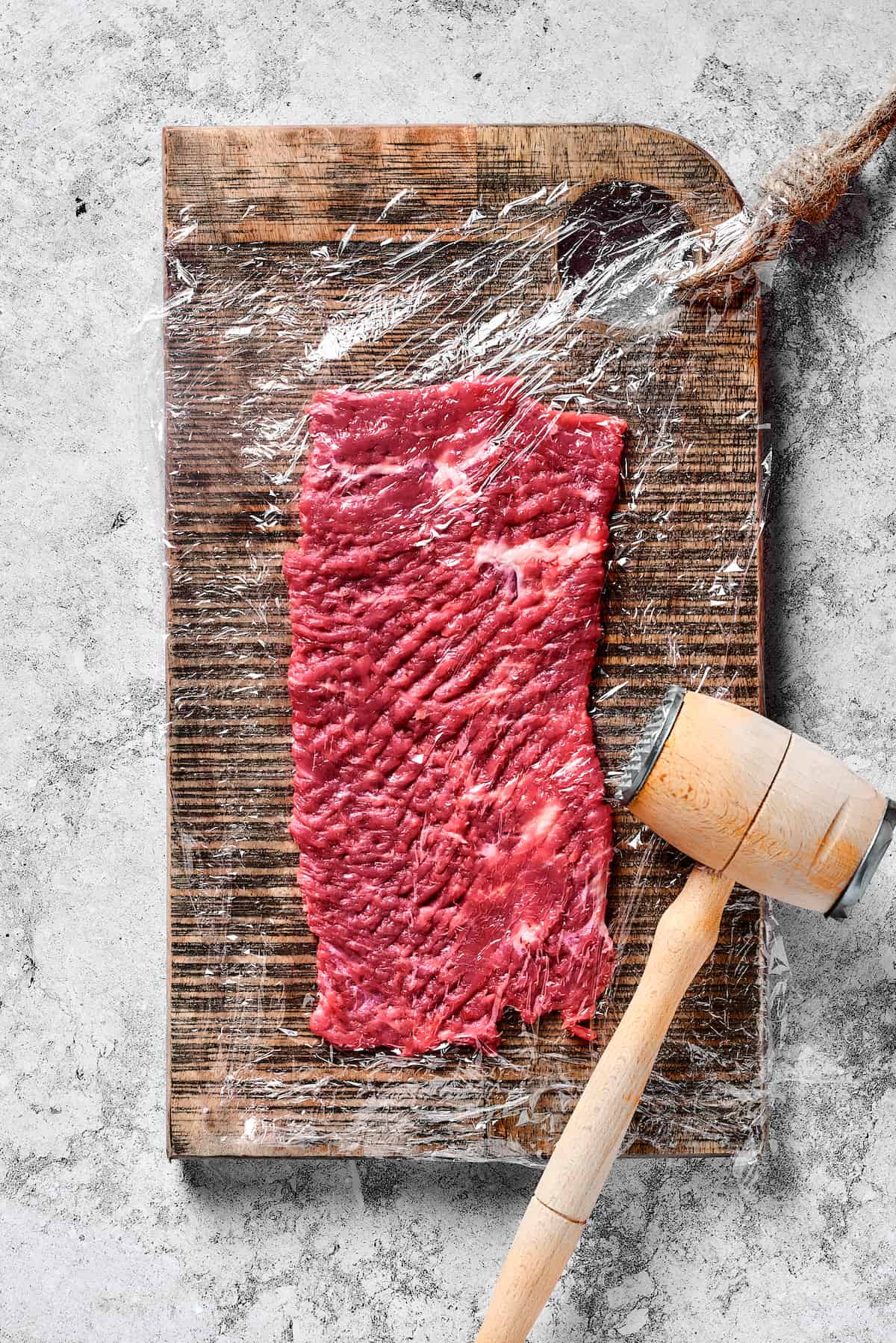 A mallet pounding strips of steak