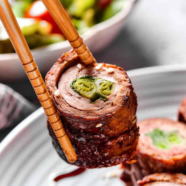Chopsticks holding a beef negimaki roll