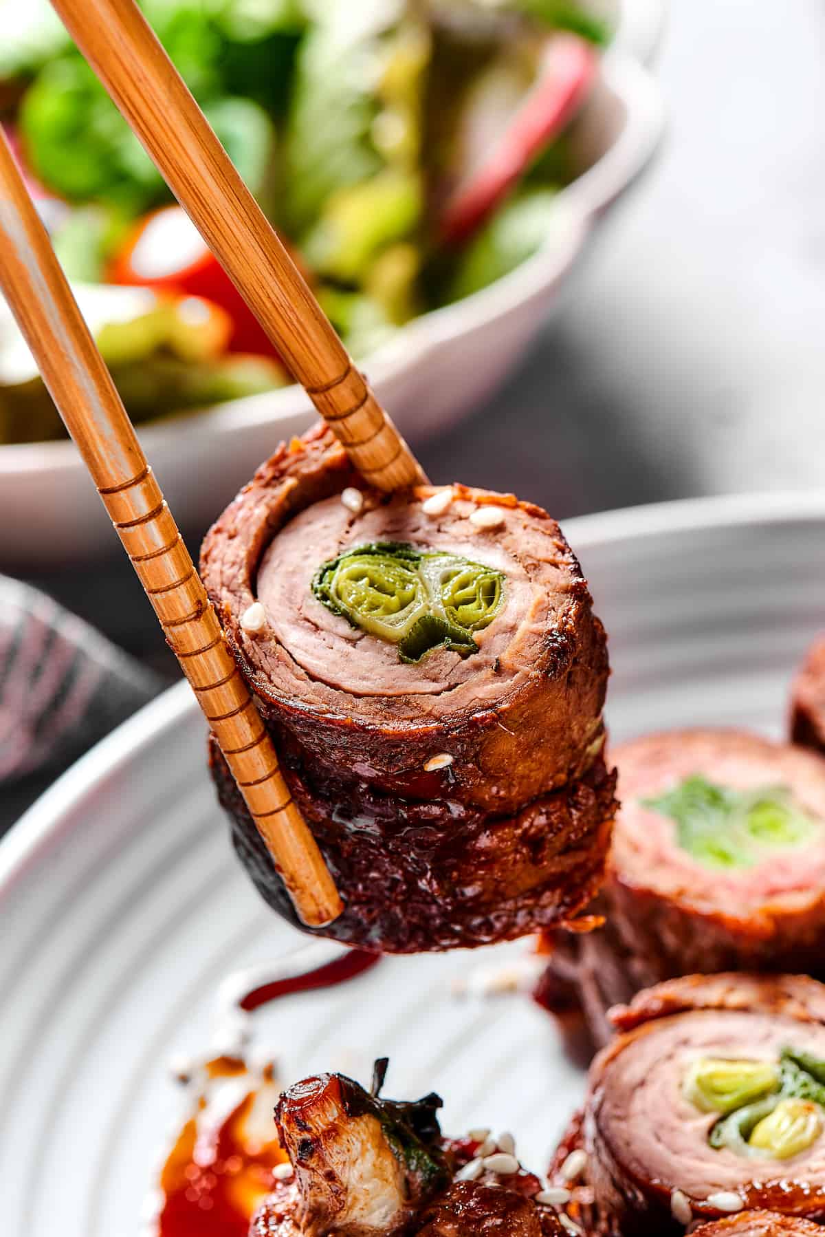 Chopsticks holding a beef negimaki roll