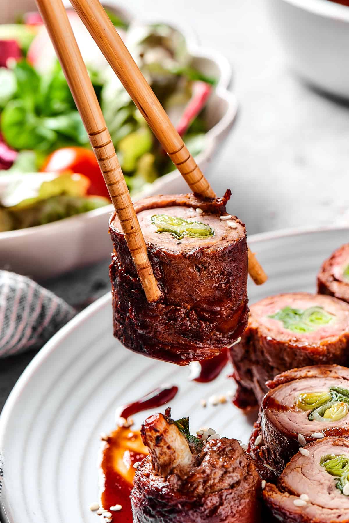 Chopsticks holding a beef negimaki roll